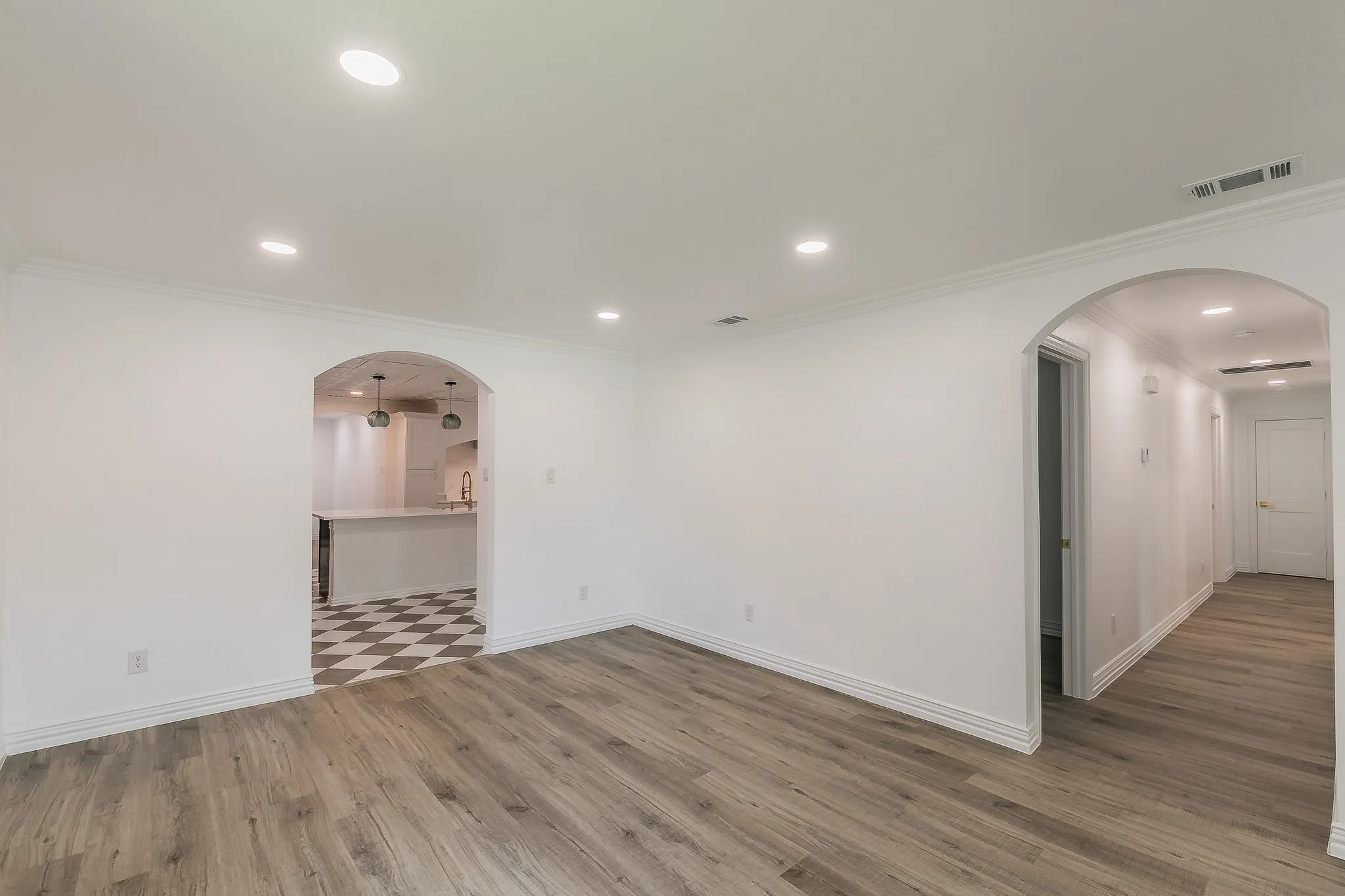 Unfurnished room with arched walkways, light wood-style floors, ornamental molding, and recessed lighting