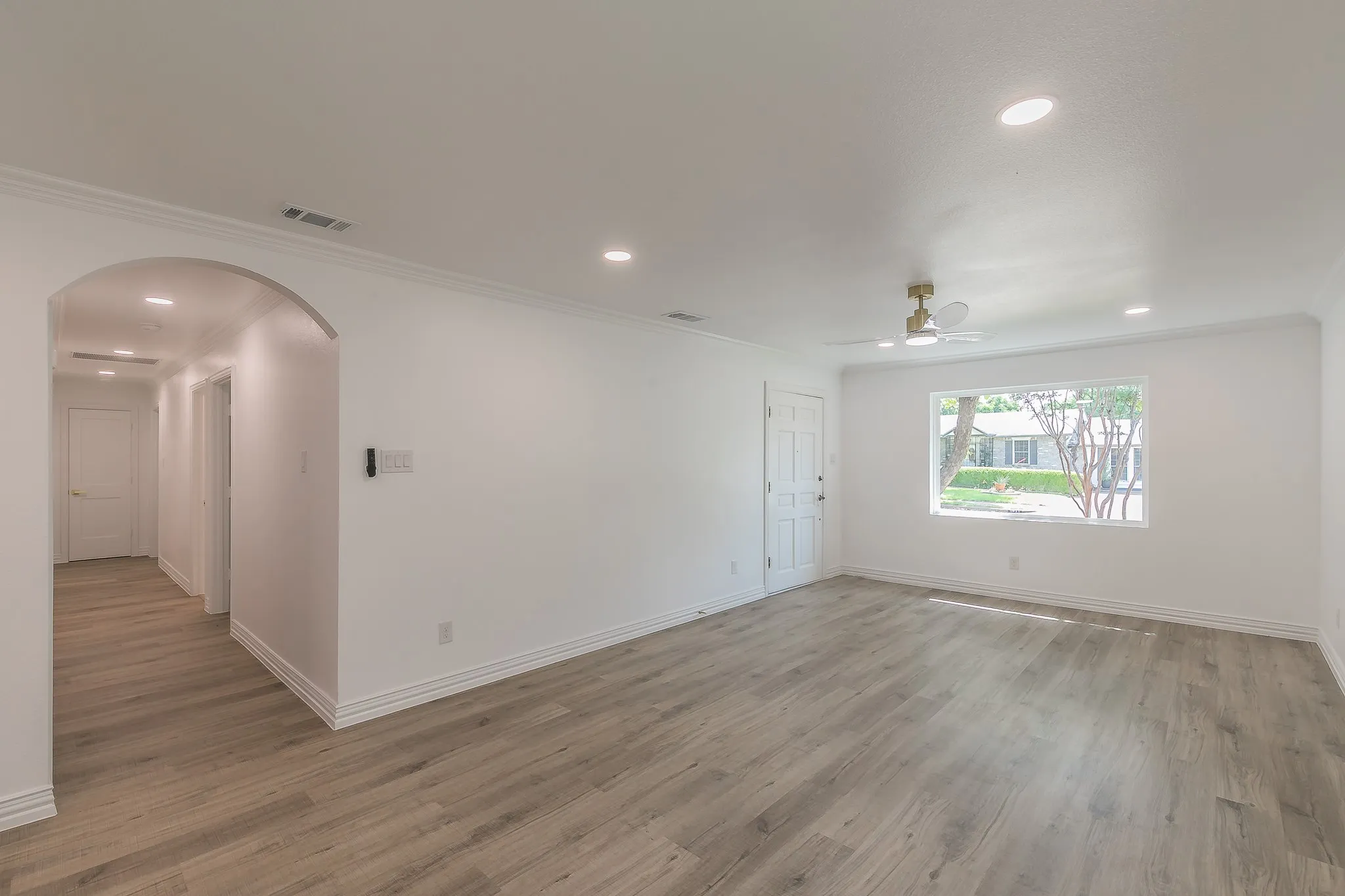 Unfurnished room with arched walkways, ornamental molding, light wood-style flooring, recessed lighting, and ceiling fan