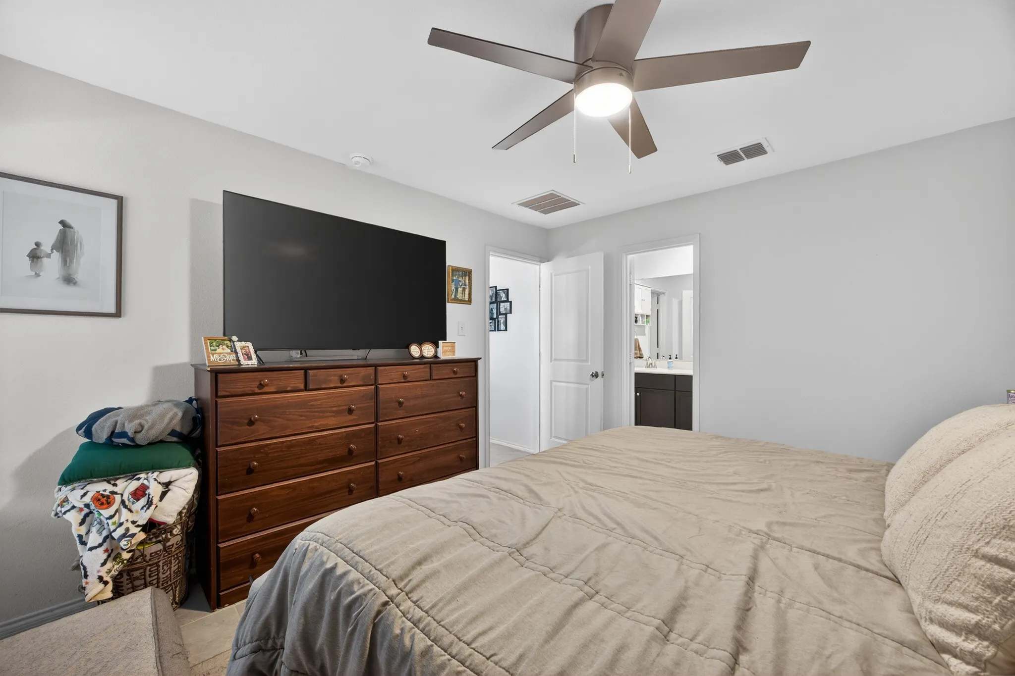 Bedroom with a ceiling fan, light colored carpet, and ensuite bathroom