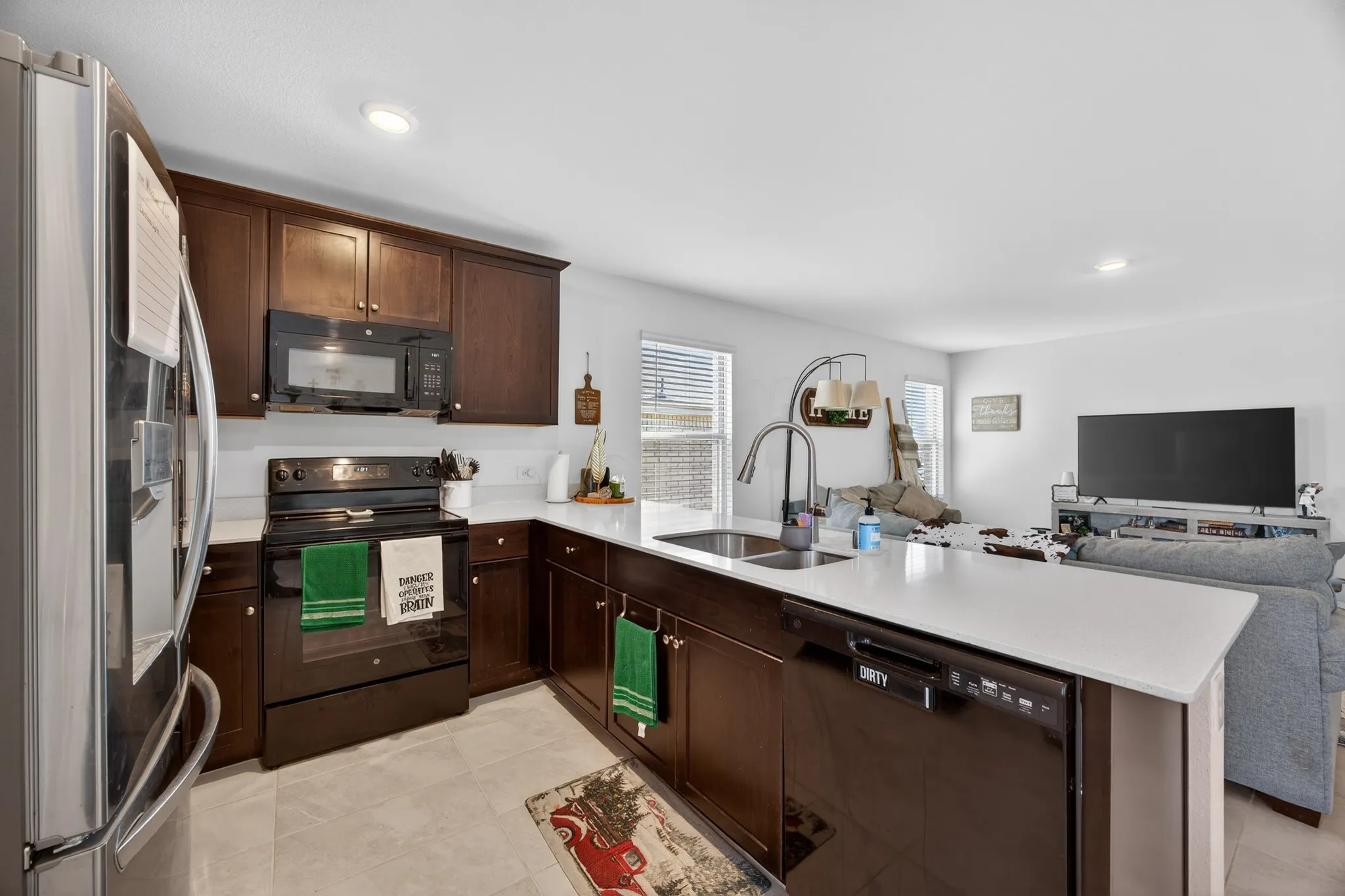 Kitchen with black appliances, open floor plan, dark brown cabinets, recessed lighting, and a peninsula