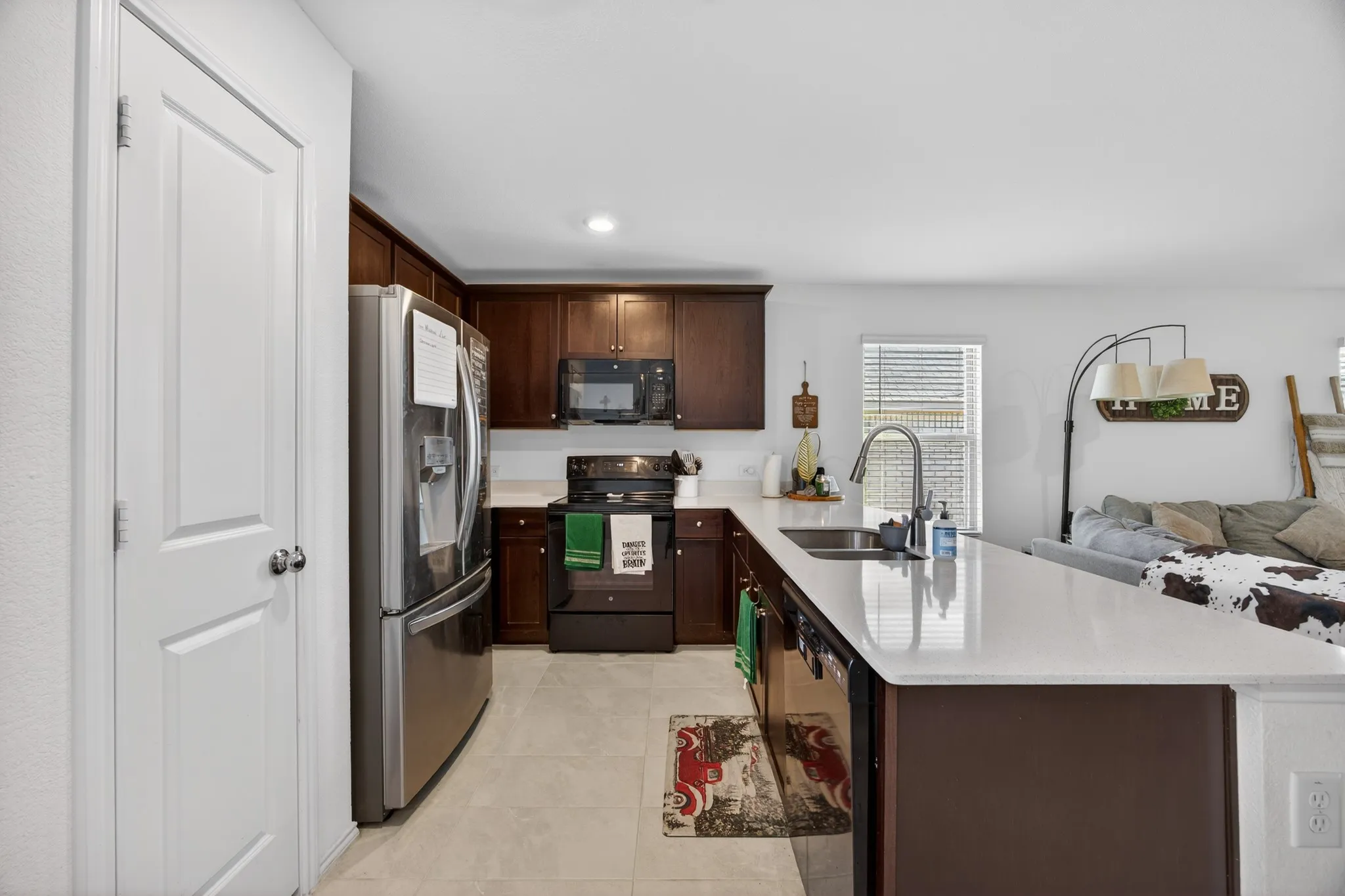 Kitchen with dark brown cabinets, black appliances, open floor plan, a peninsula, and recessed lighting