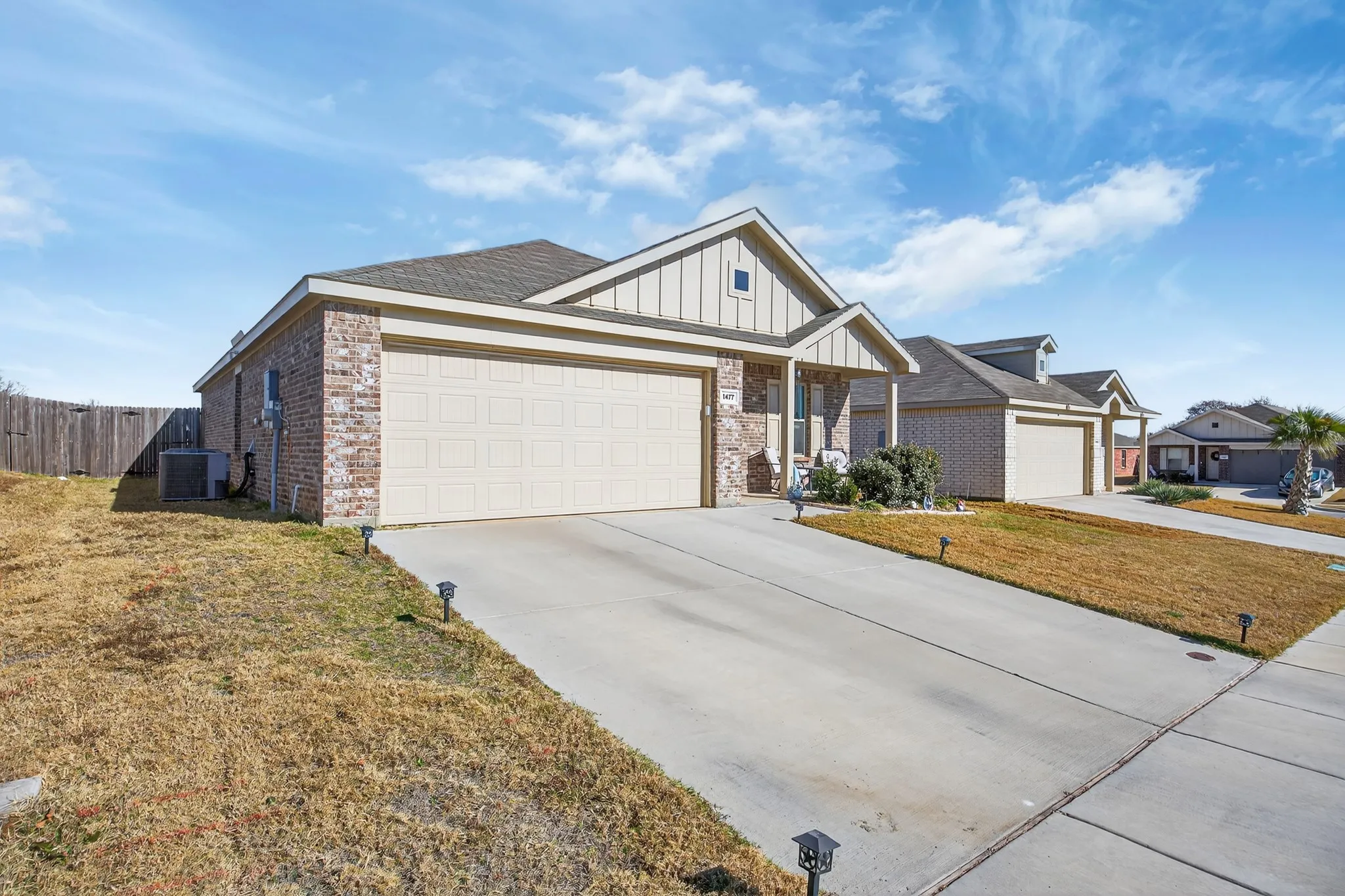View of front facade with board and batten siding, brick siding, concrete driveway, an attached garage, and a porch