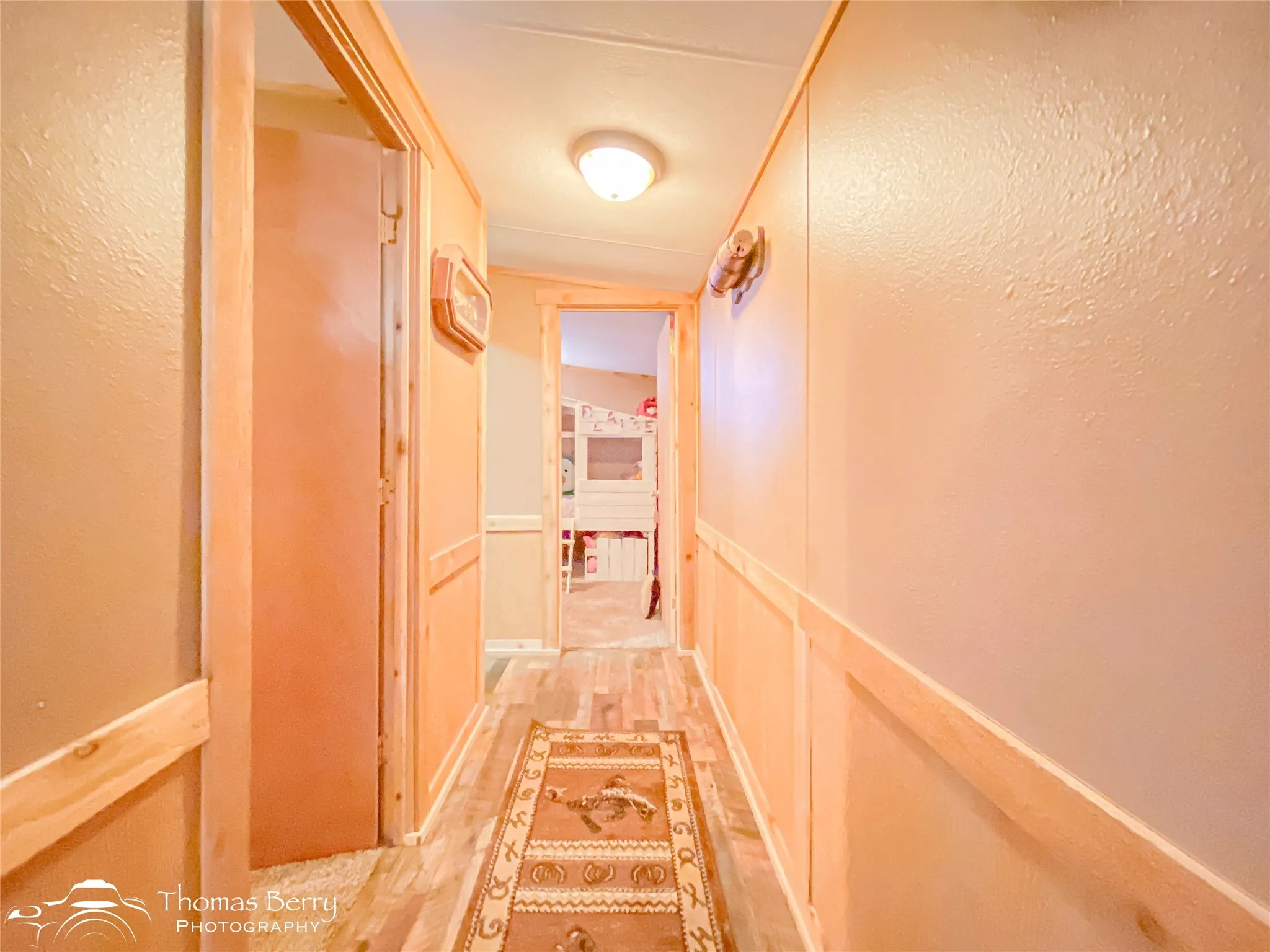 Hall with a textured wall, a wainscoted wall, a decorative wall, and light wood-style floors