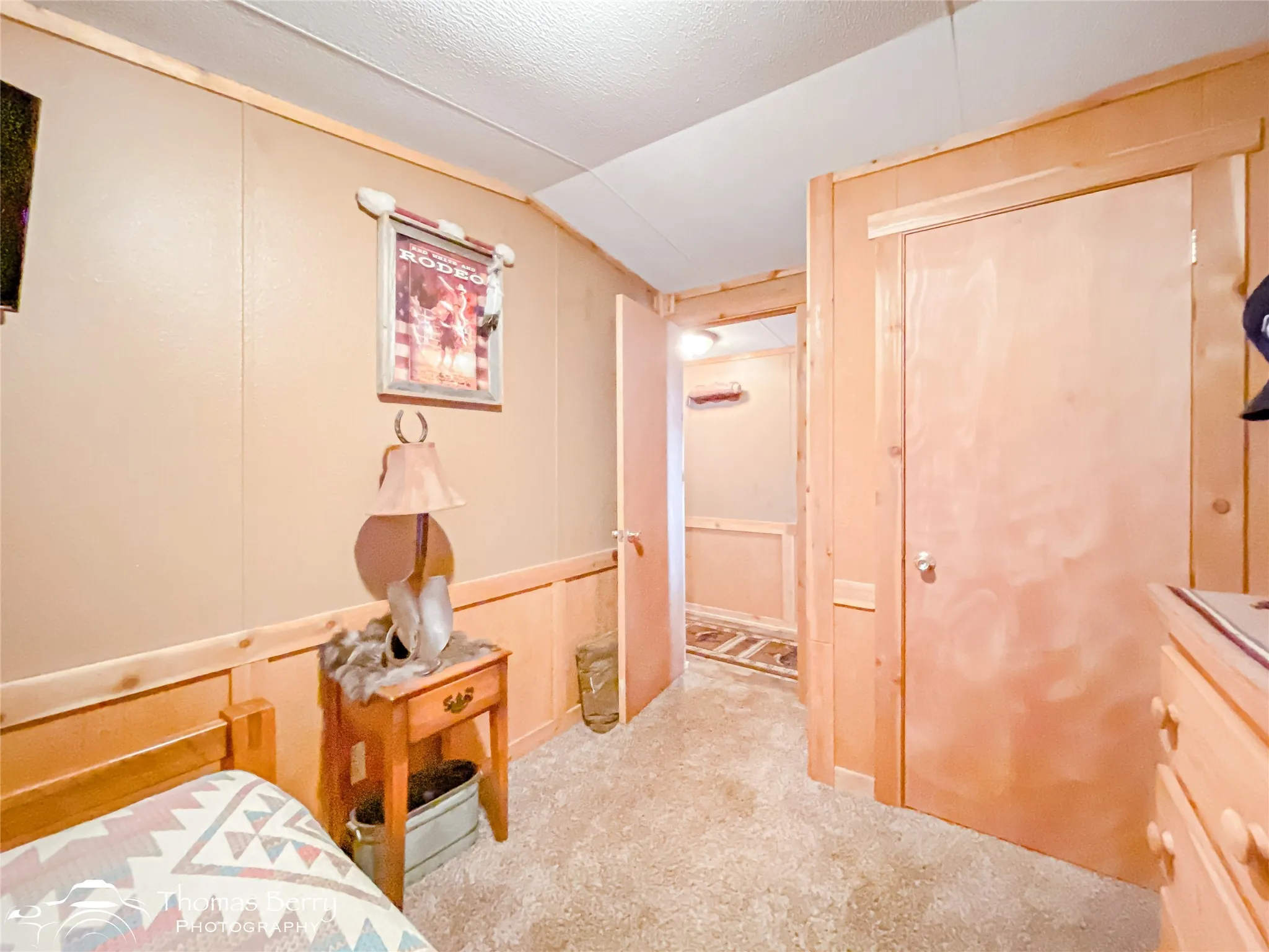 Carpeted bedroom with a decorative wall, lofted ceiling, and a textured ceiling