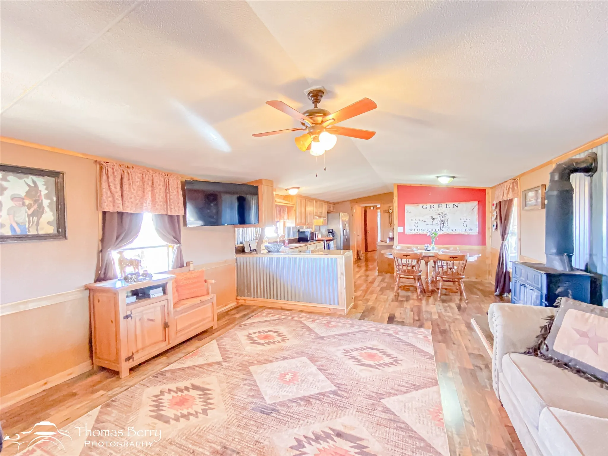 Kitchen with light brown cabinetry, light wood-type flooring, vaulted ceiling, light countertops, and stainless steel fridge with ice dispenser