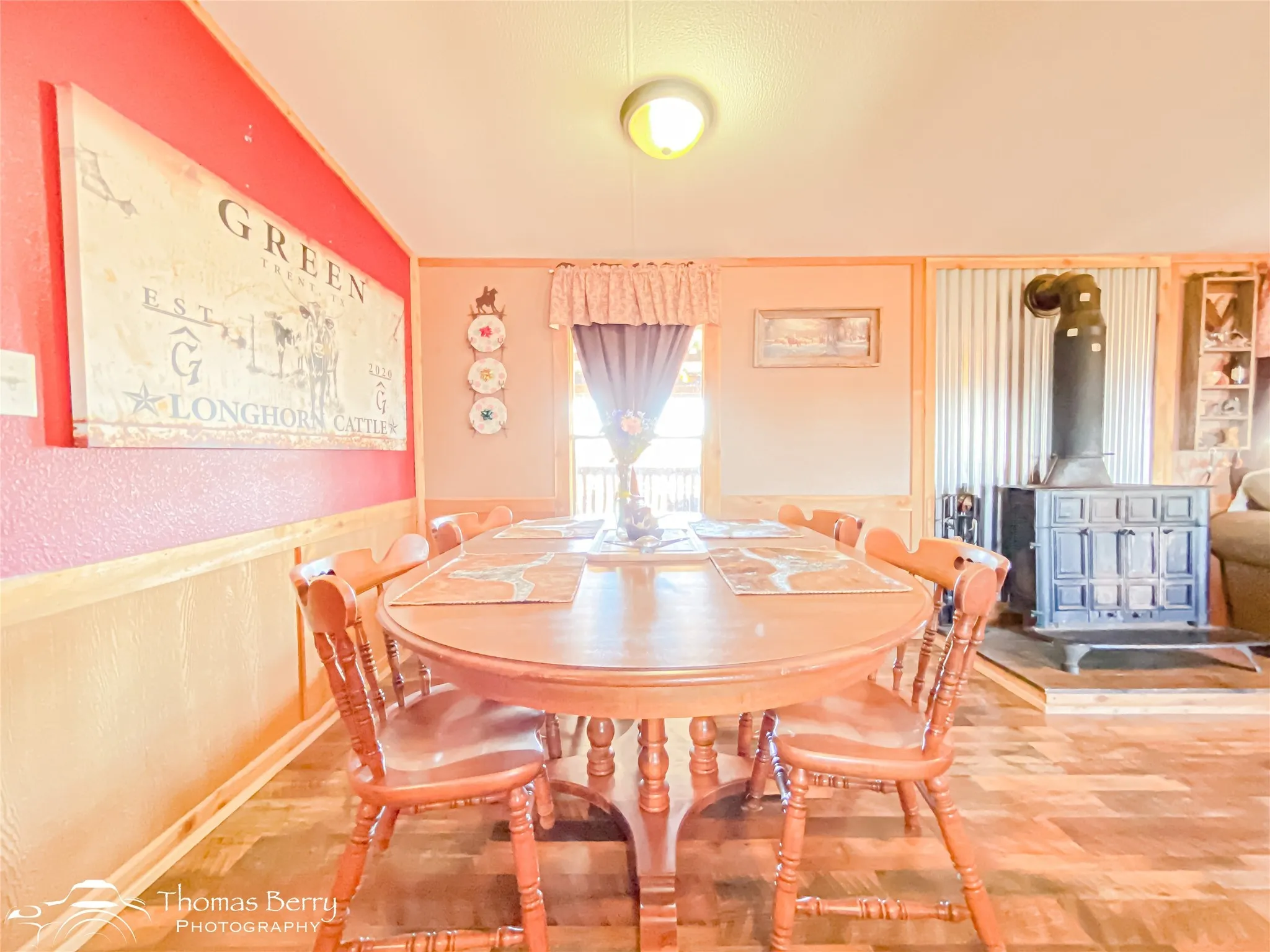 Dining area with a wood stove and wood finished floors