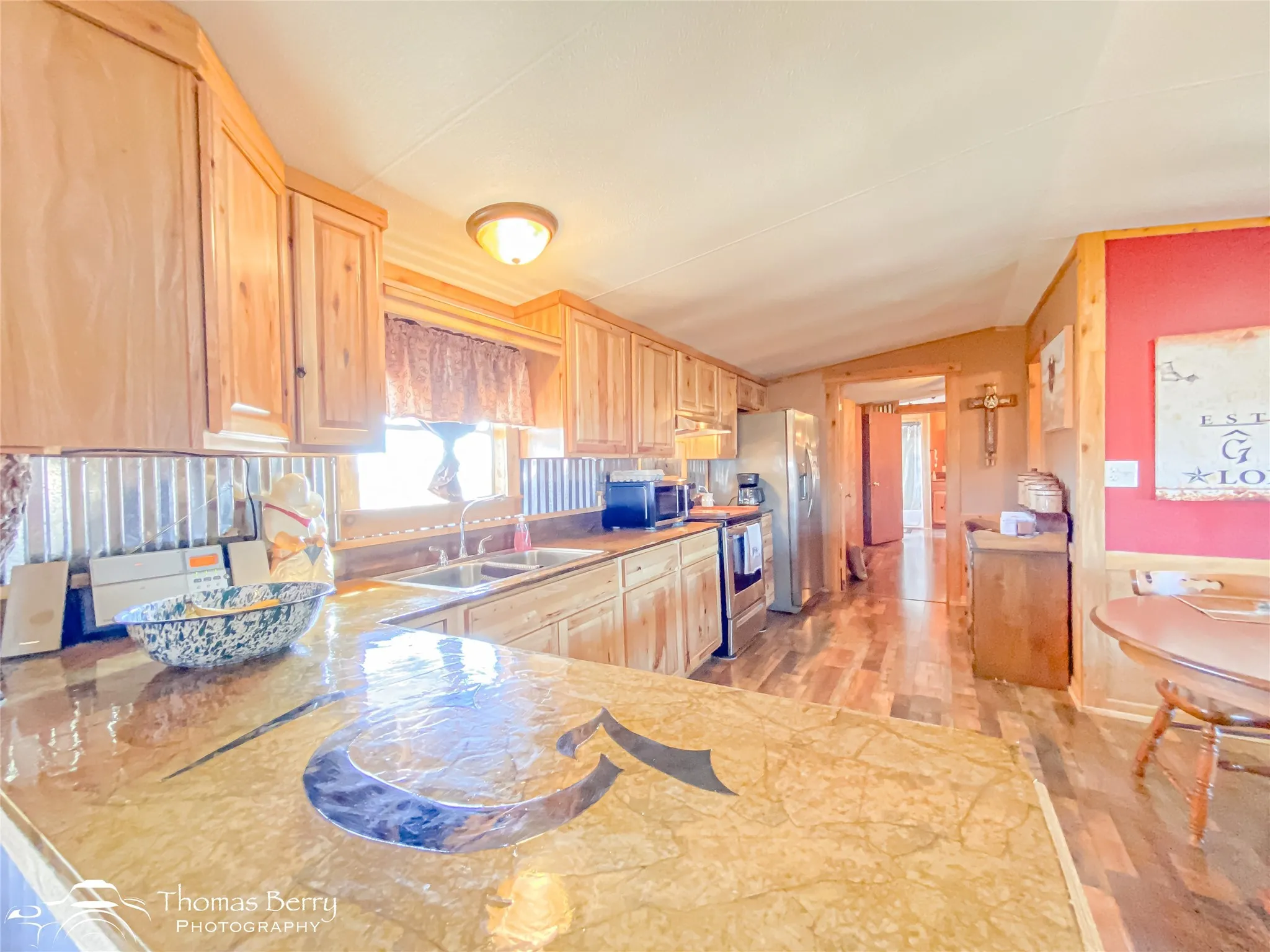 Kitchen featuring light brown cabinets, light wood-style floors, appliances with stainless steel finishes, and vaulted ceiling