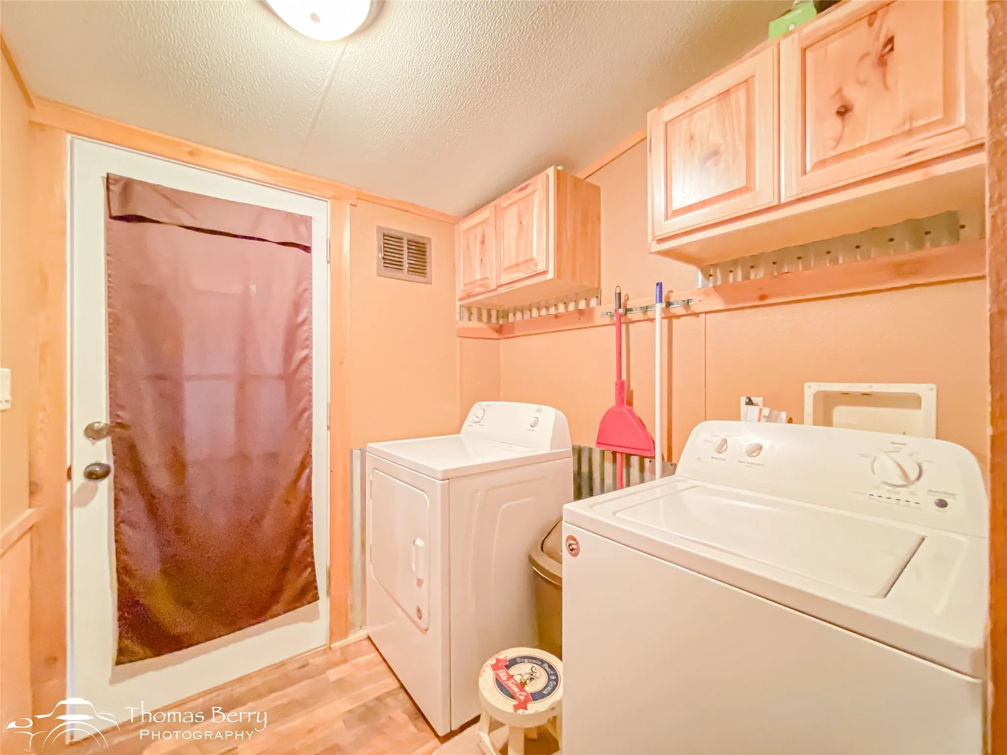 Laundry room featuring a textured ceiling, washer and dryer, light wood-type flooring, and cabinet space