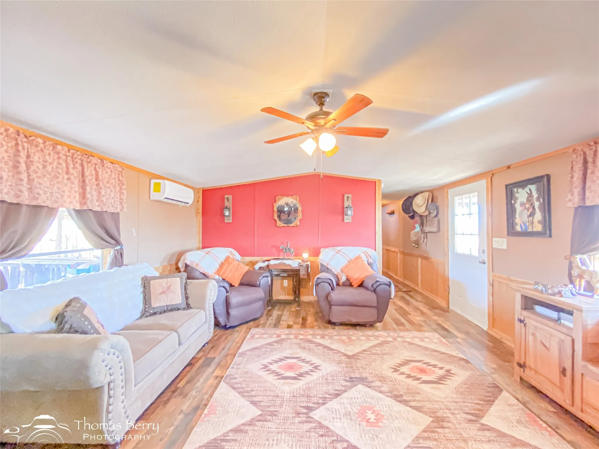 Living area featuring a decorative wall, light wood-style floors, ceiling fan, lofted ceiling, and a wall unit AC