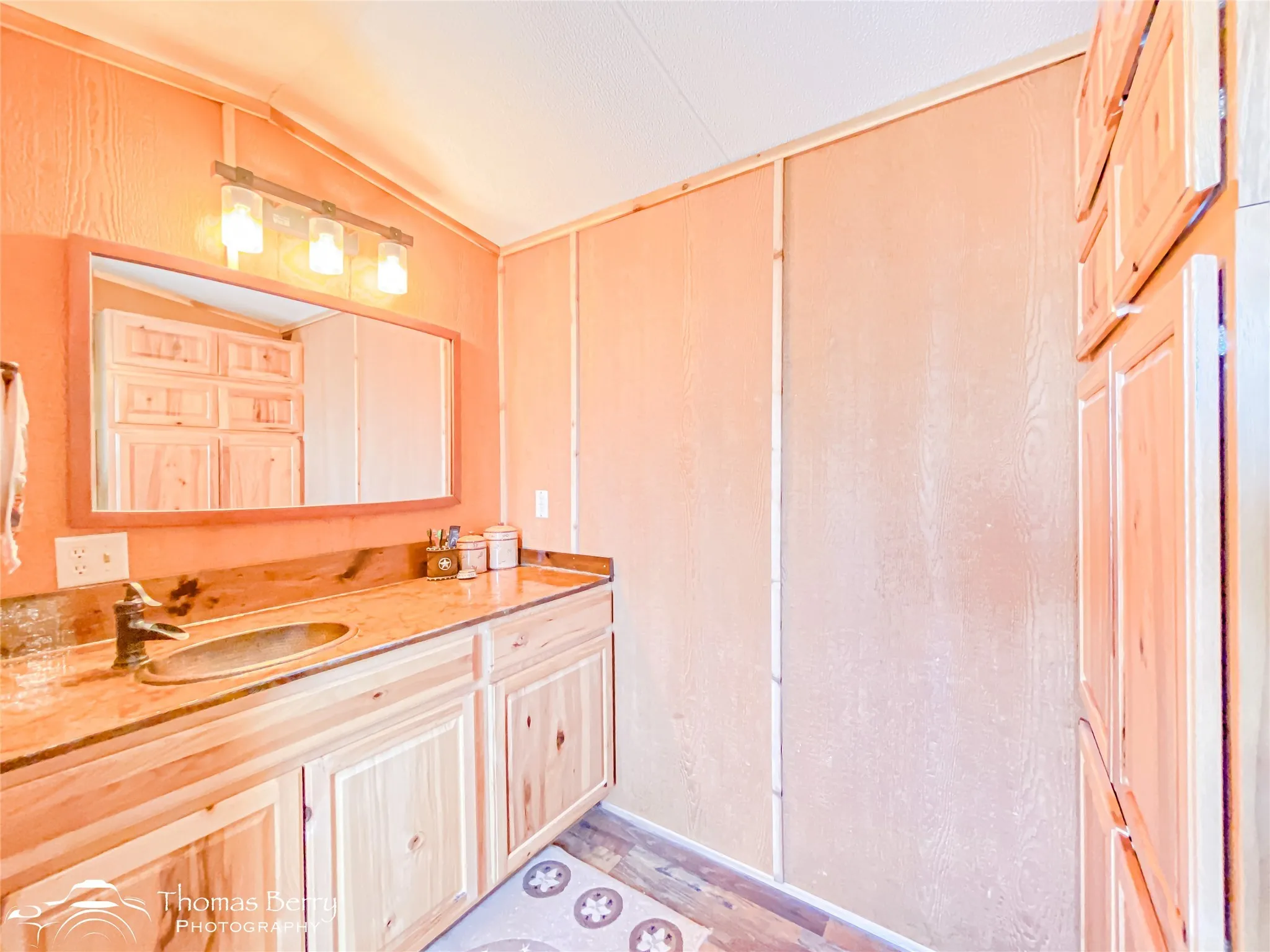 Bathroom featuring vanity, vaulted ceiling, and light wood-style flooring