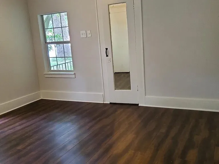 Unfurnished bedroom with baseboards and dark wood finished floors