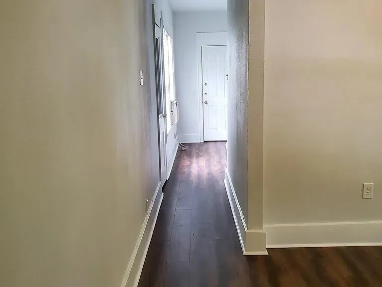 Corridor featuring baseboards and dark wood-type flooring
