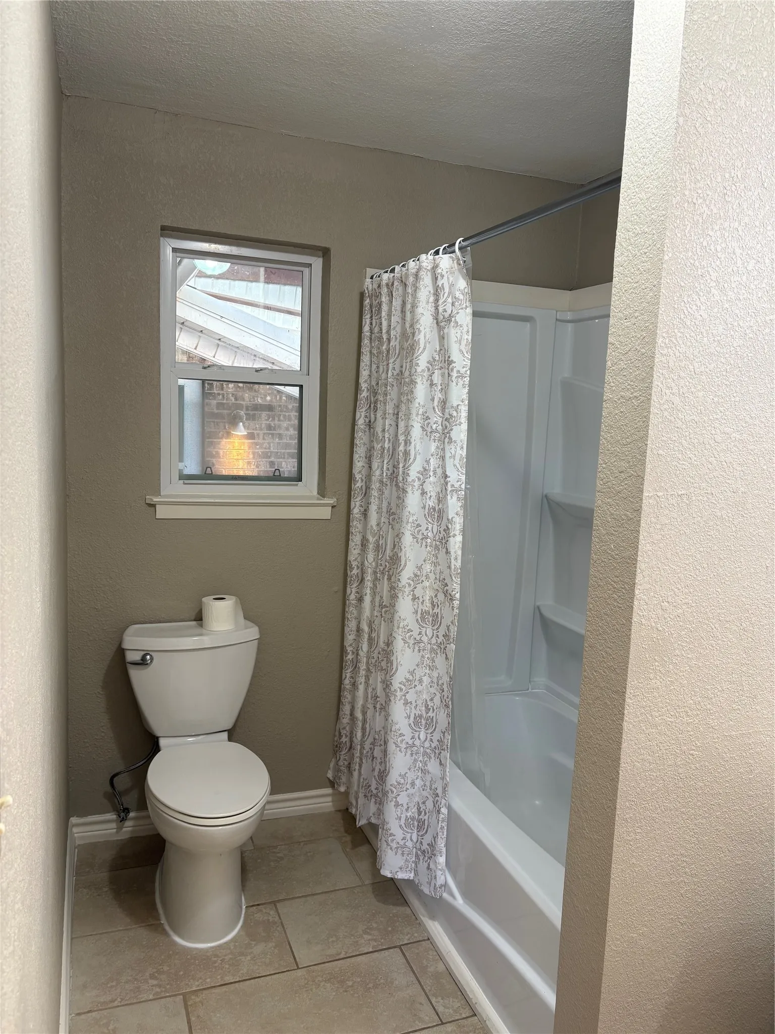 Full bathroom with shower / bath combination with curtain, a textured ceiling, a textured wall, and light tile patterned floors