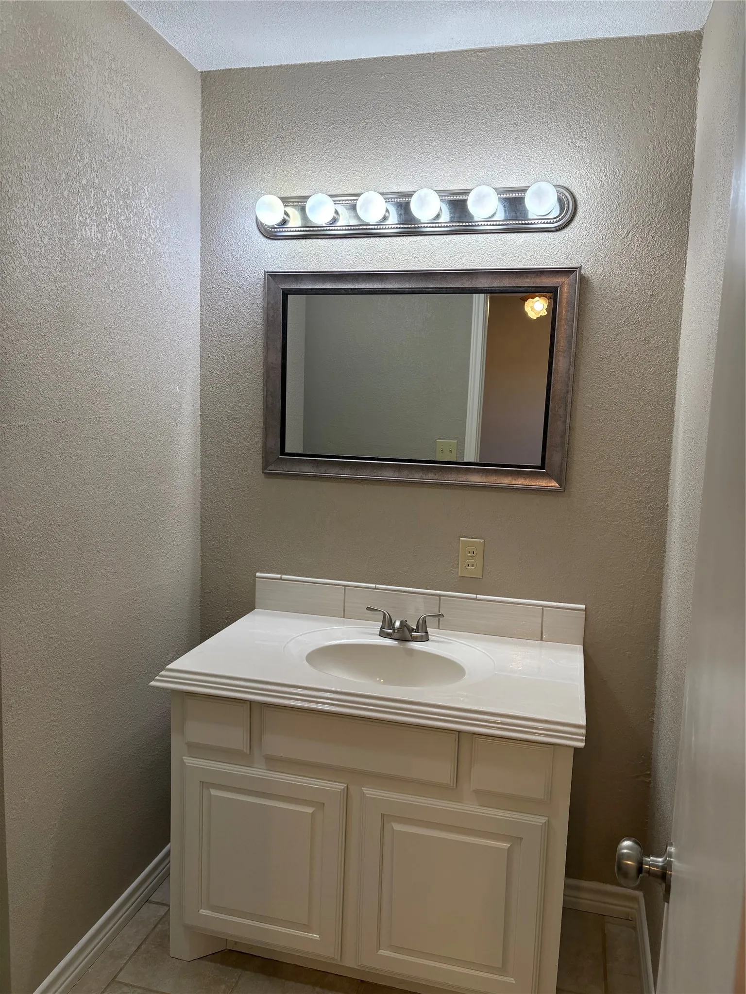 Bathroom featuring a textured wall, vanity, and light tile patterned flooring