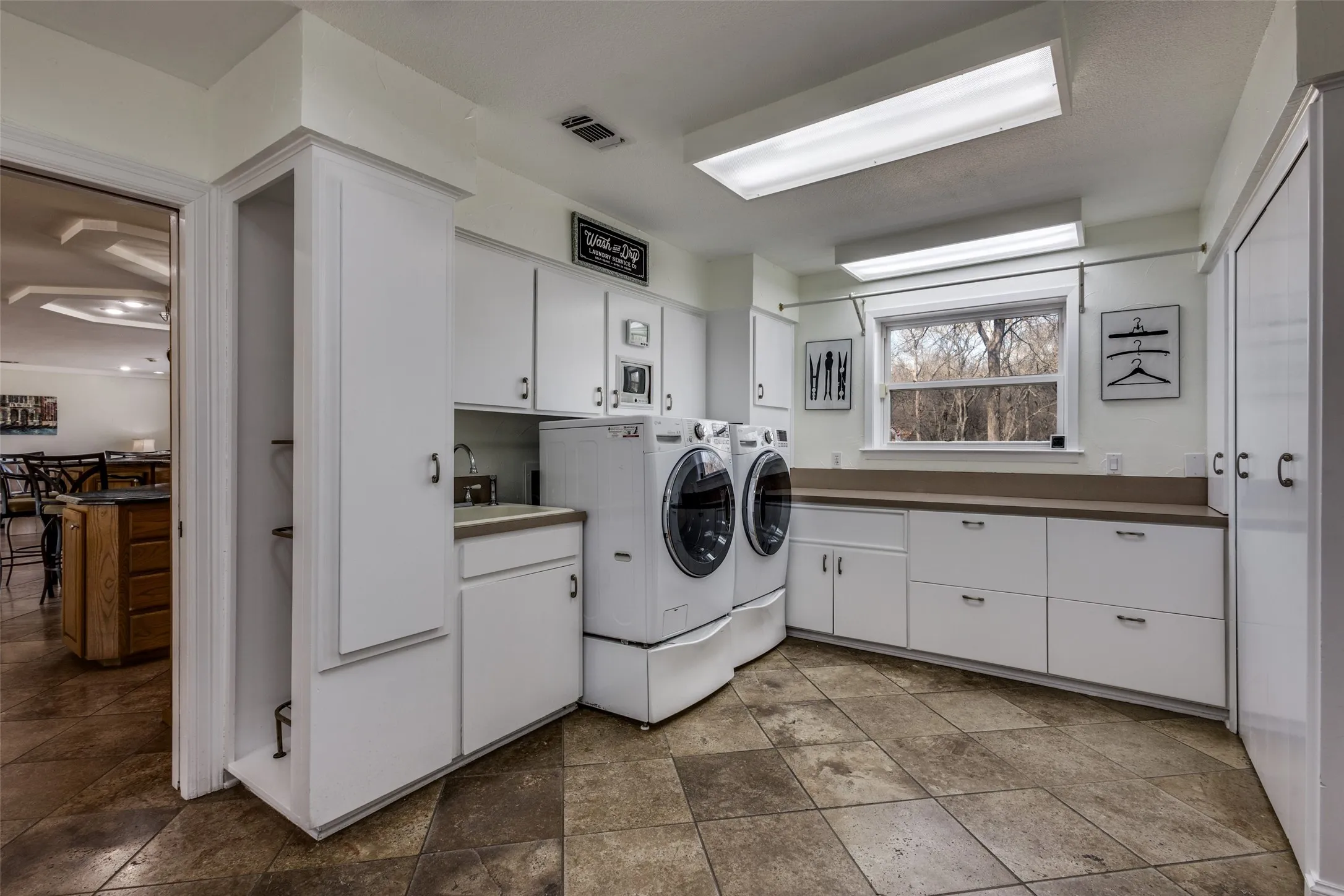 Spacious laundry room with abundant storage, utility sink, built-in desk, and natural light. Designed for functional household organization.