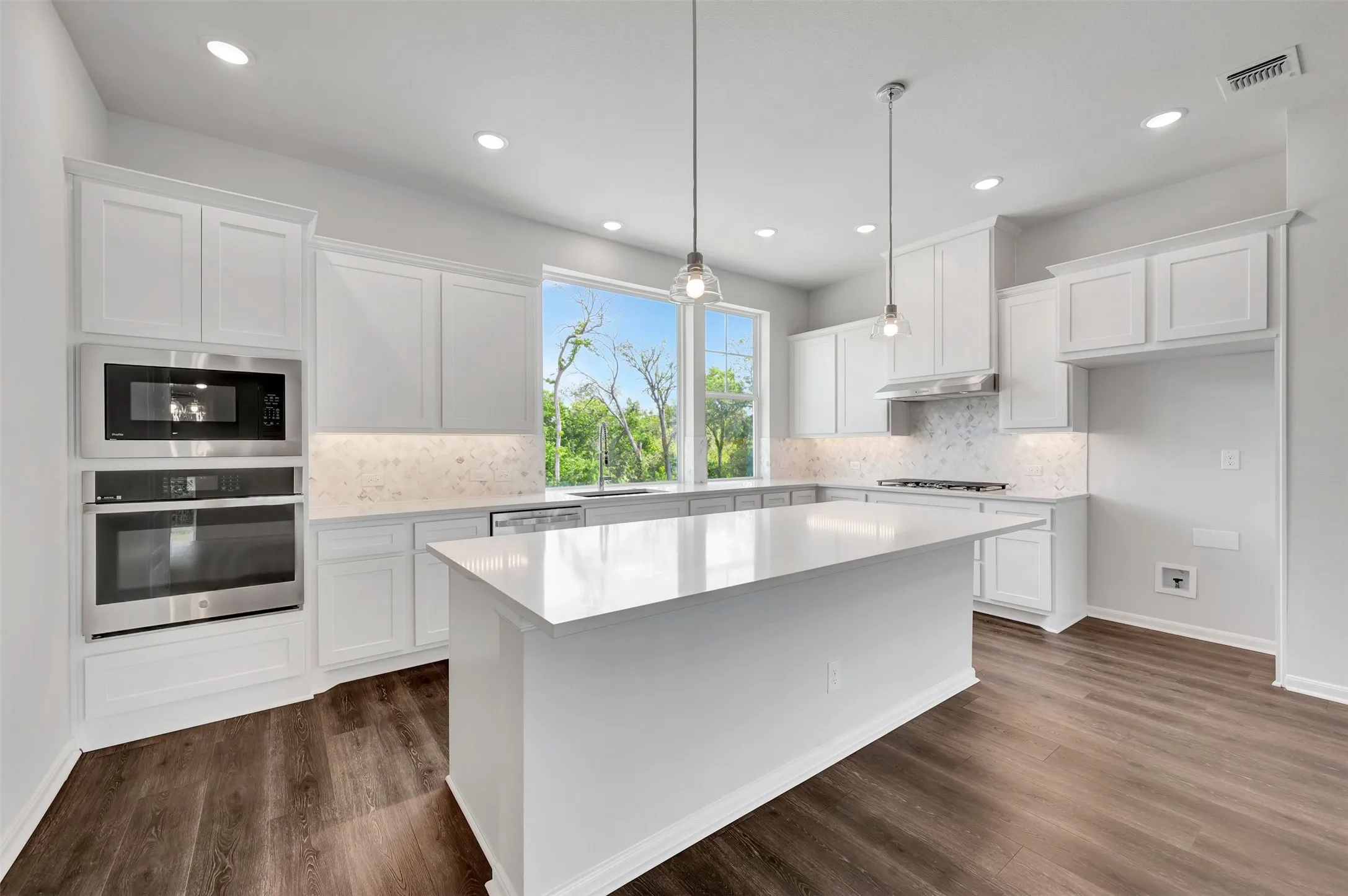 Kitchen featuring white cabinetry, wood-finish flooring, recessed lighting, and a center island with pendant lights
