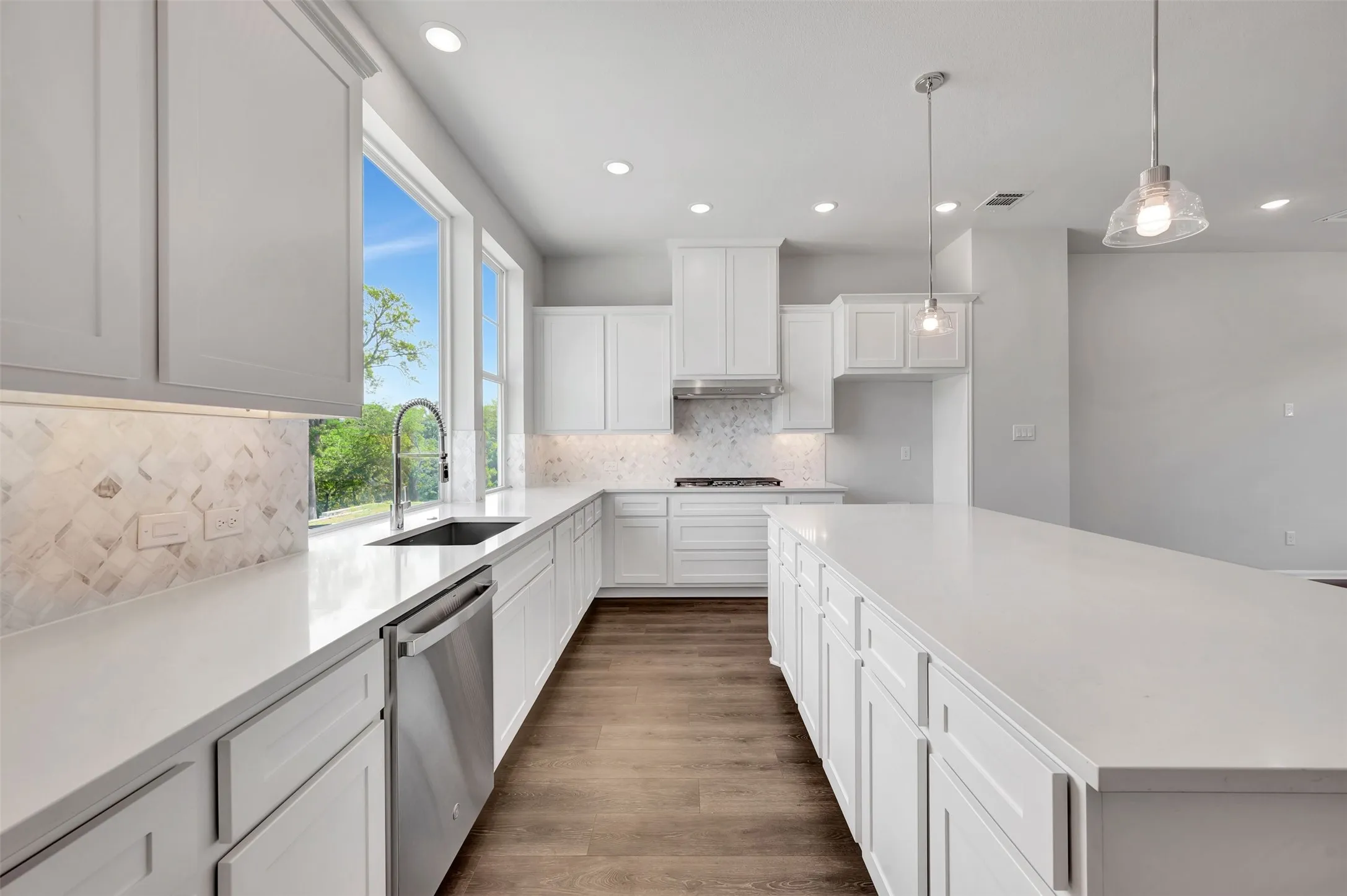 Modern kitchen featuring abundant white cabinetry, white countertops, stainless steel appliances, a decorative tile backsplash, and wood-finish flooring