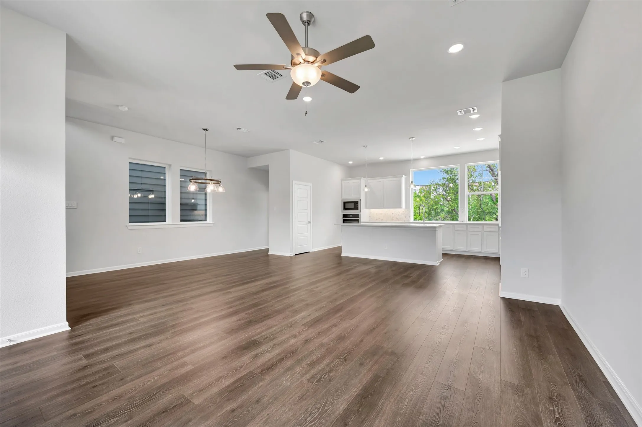 Open-concept living area featuring wood-finish flooring, recessed lighting, and a contemporary ceiling fan