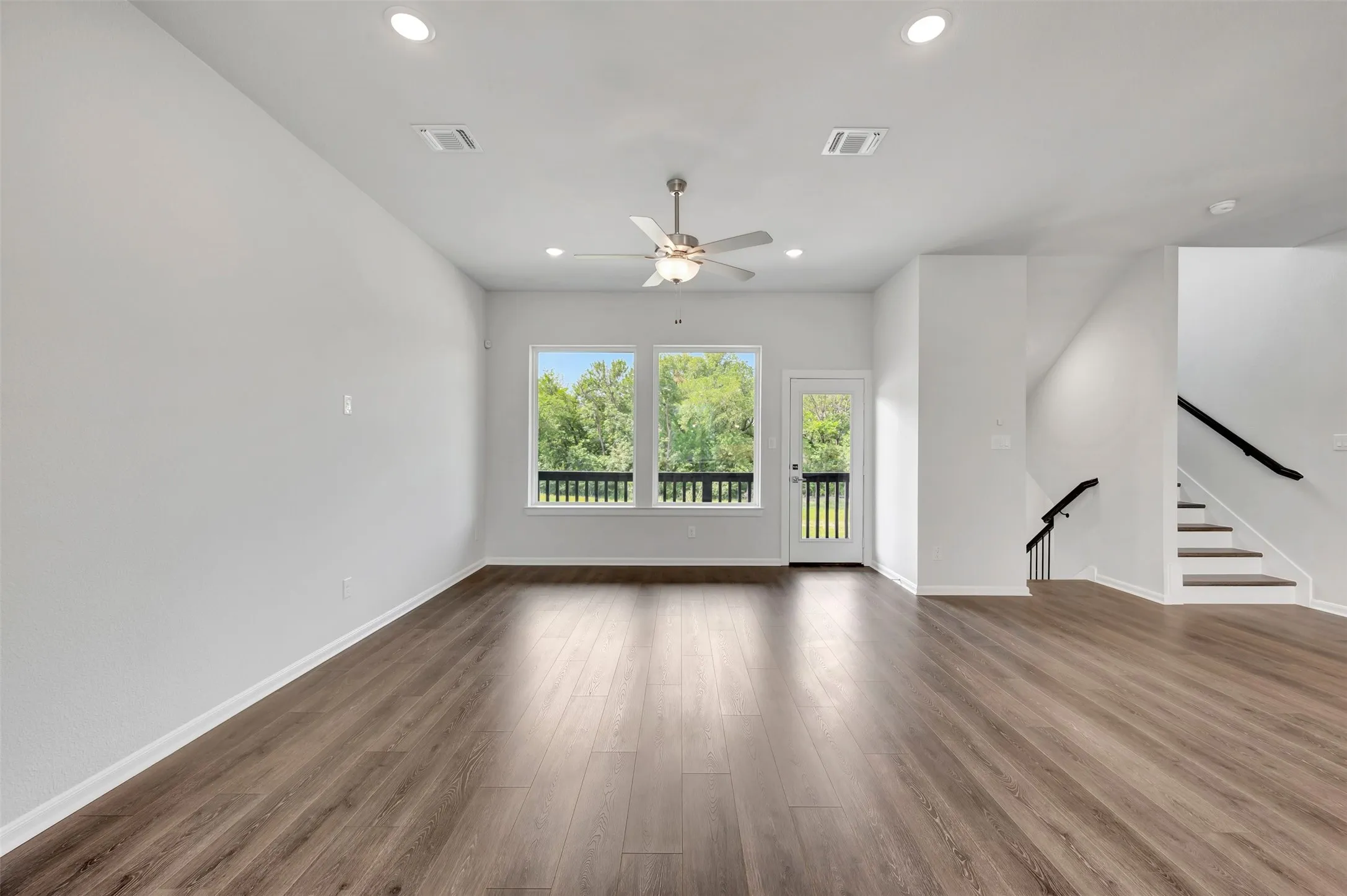 Spacious room featuring wood-finish flooring, recessed lighting, and a ceiling fan