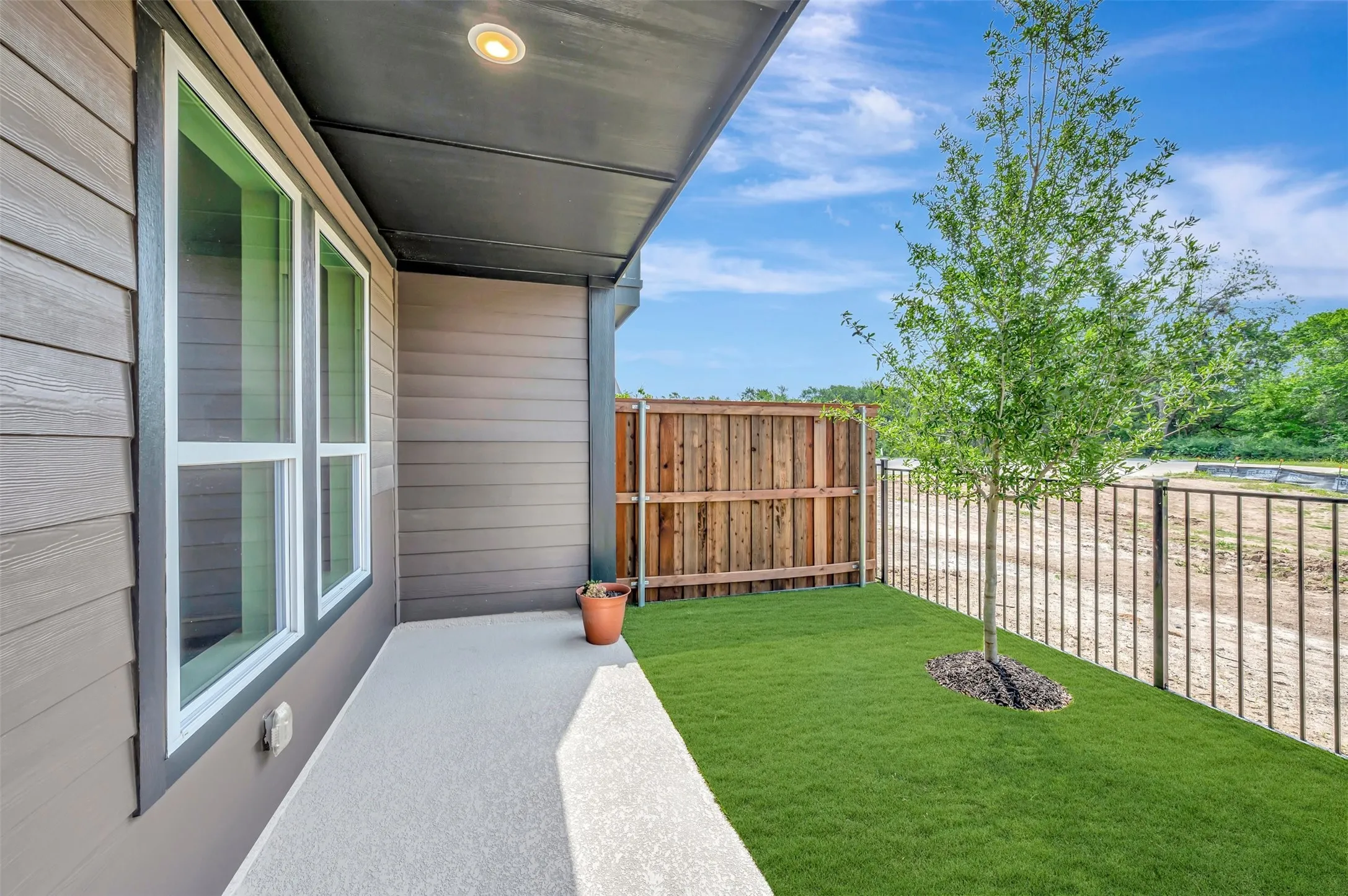 Exterior patio featuring a covered area with recessed lighting, a concrete surface, and a fenced turf section