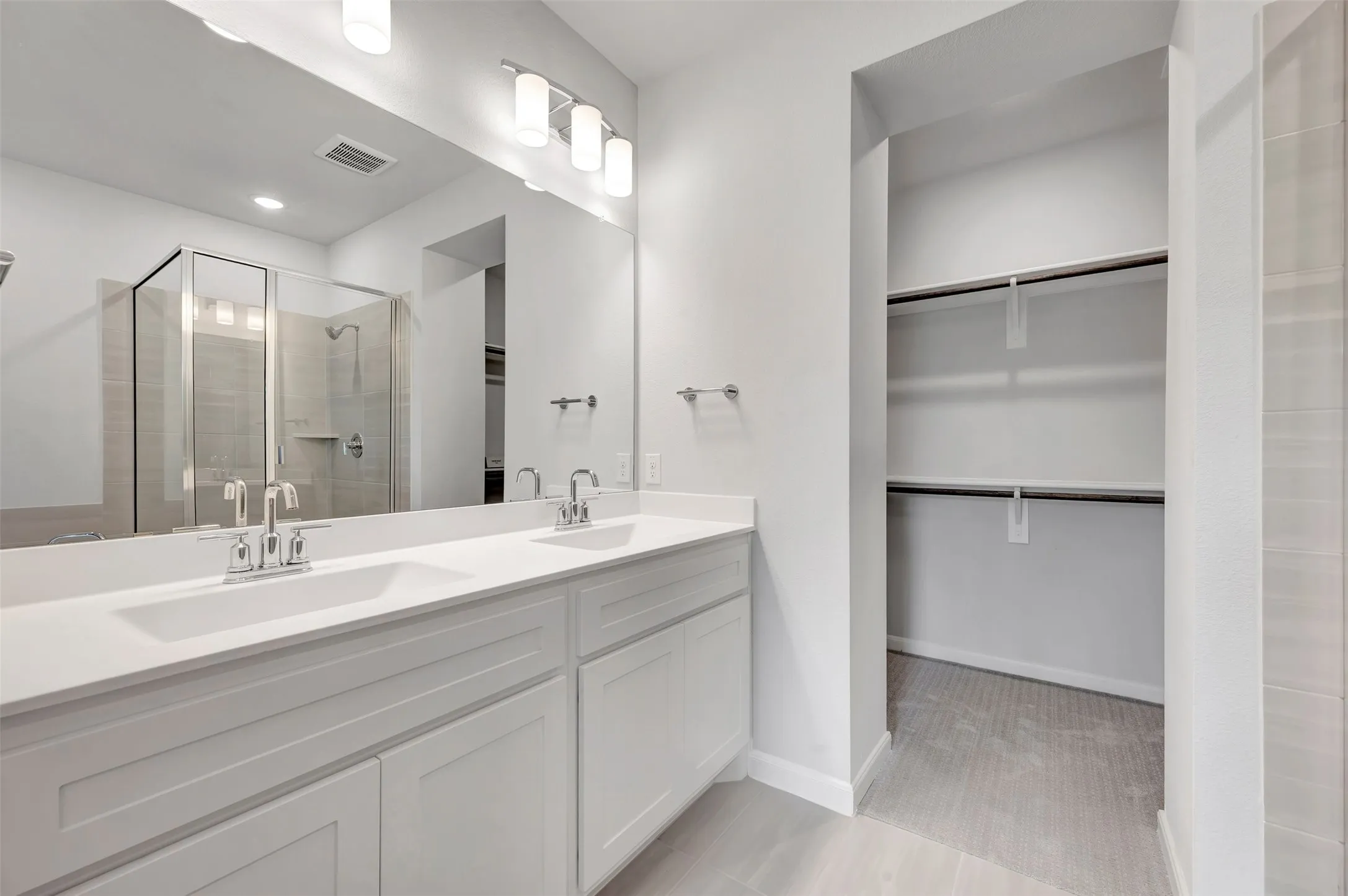 Dual vanity with white cabinetry and integrated sinks, complemented by a large wall mirror and contemporary overhead lighting