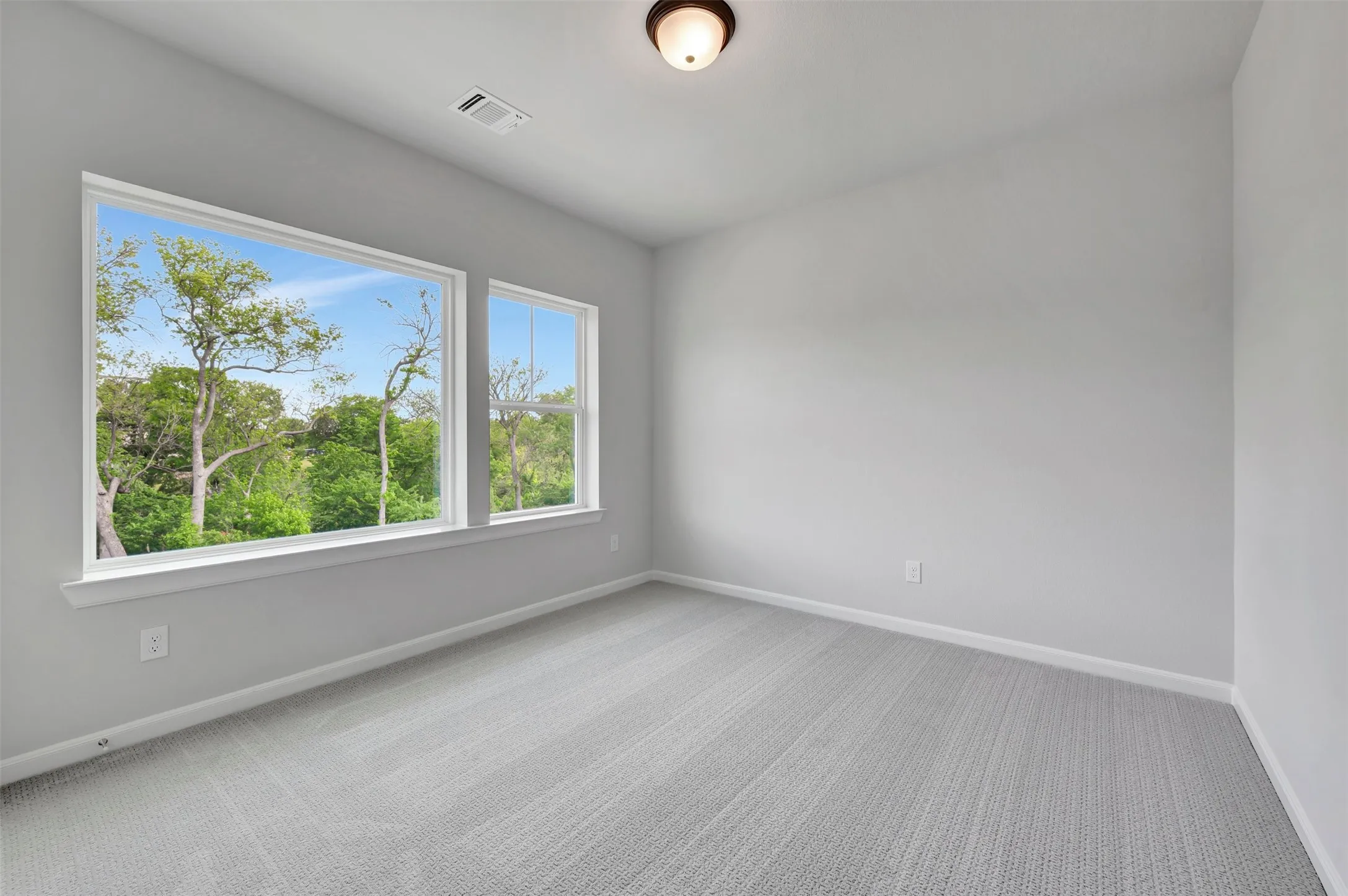 Room with two windows, light gray walls, and textured gray carpeting