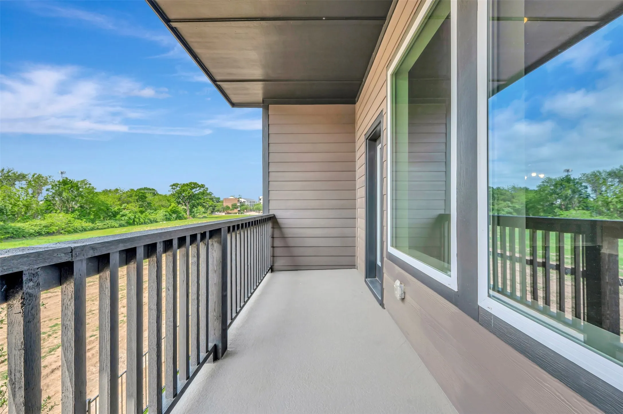 Private balcony featuring a dark wood-finish railing, a concrete surface, and wood-paneled siding