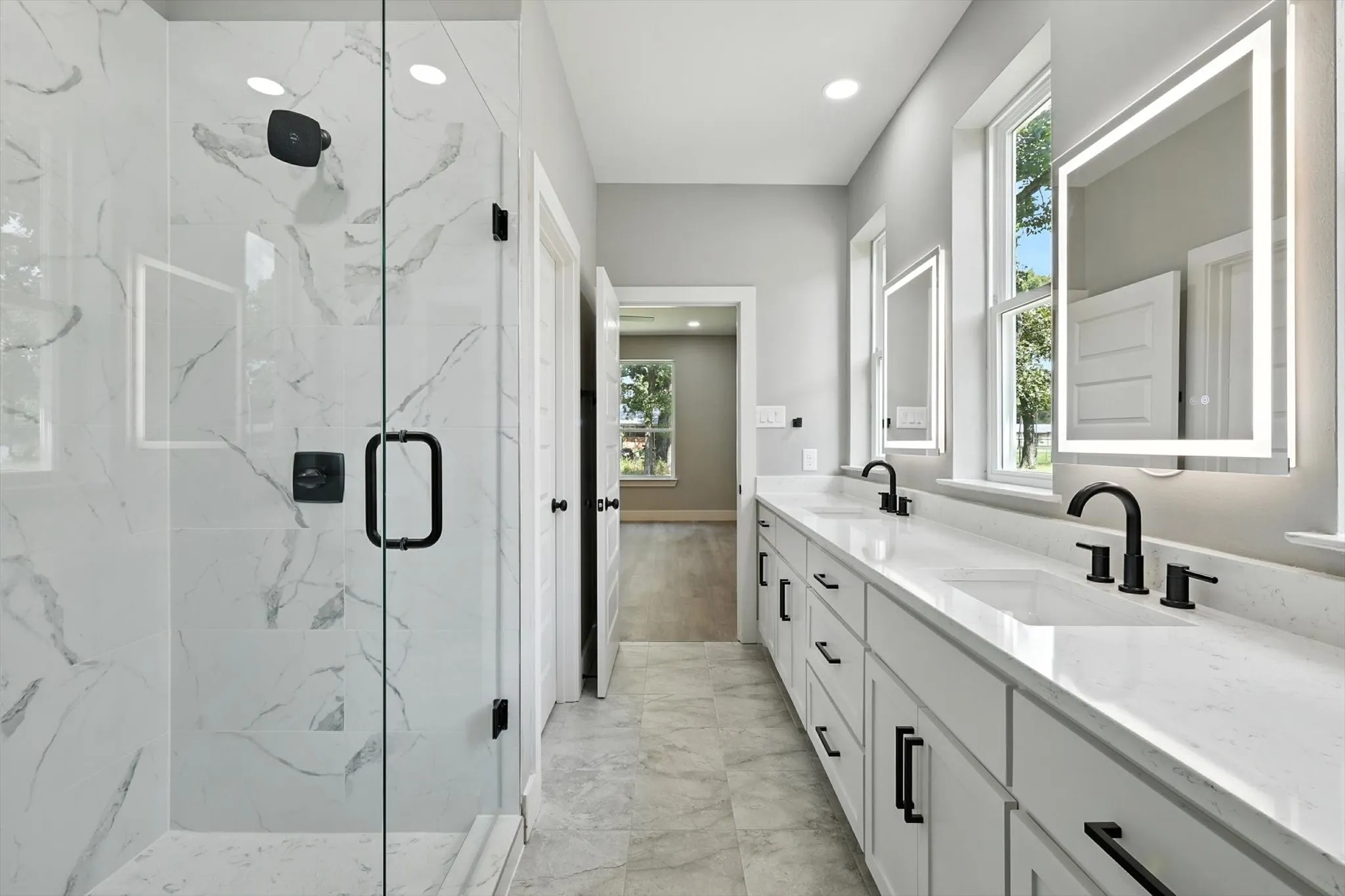 Bathroom featuring a marble finish shower, double vanity, plenty of natural light, recessed lighting, and light marble finish flooring