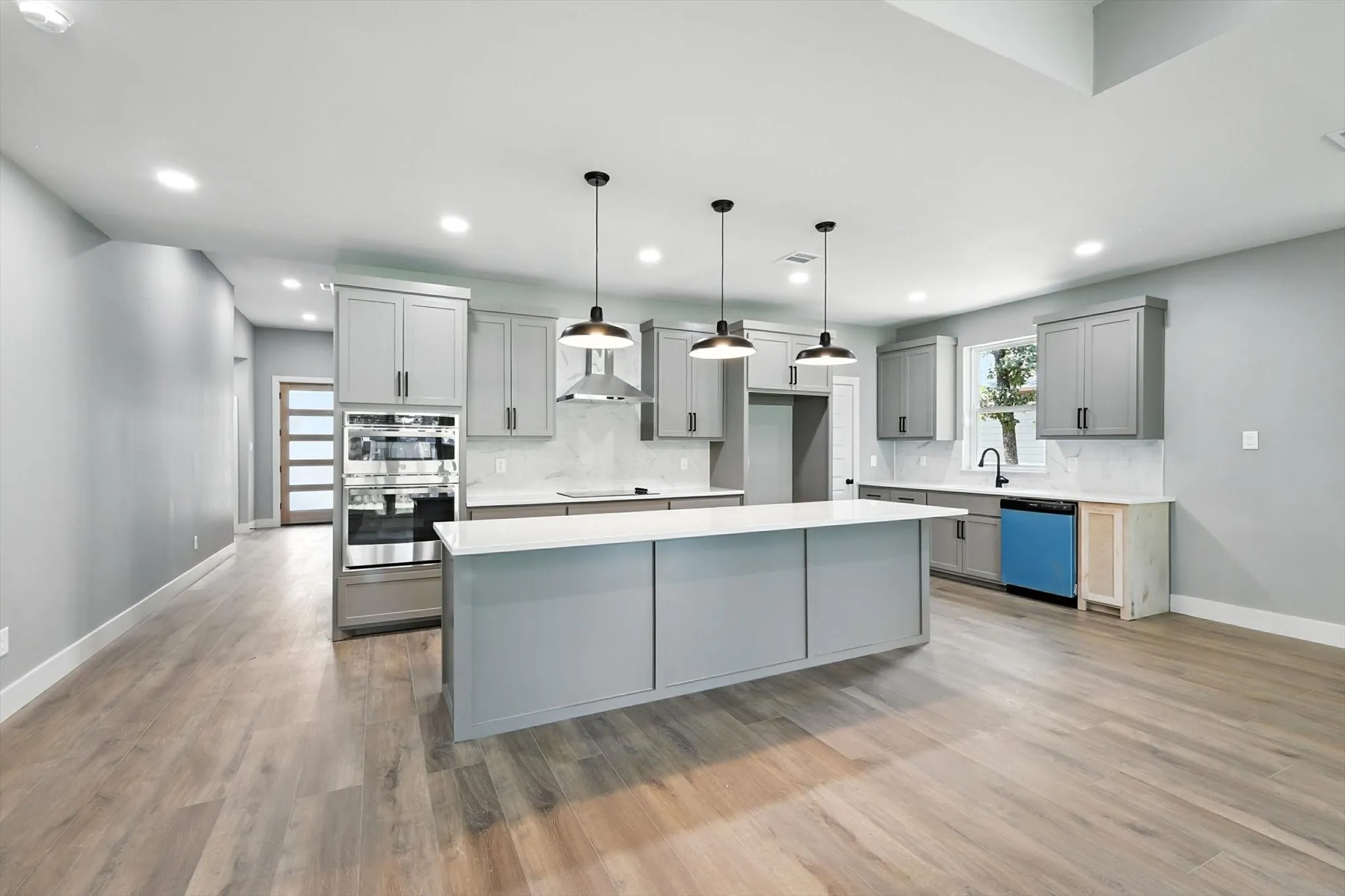 Kitchen with gray cabinetry, hanging light fixtures, backsplash, a kitchen island, and recessed lighting