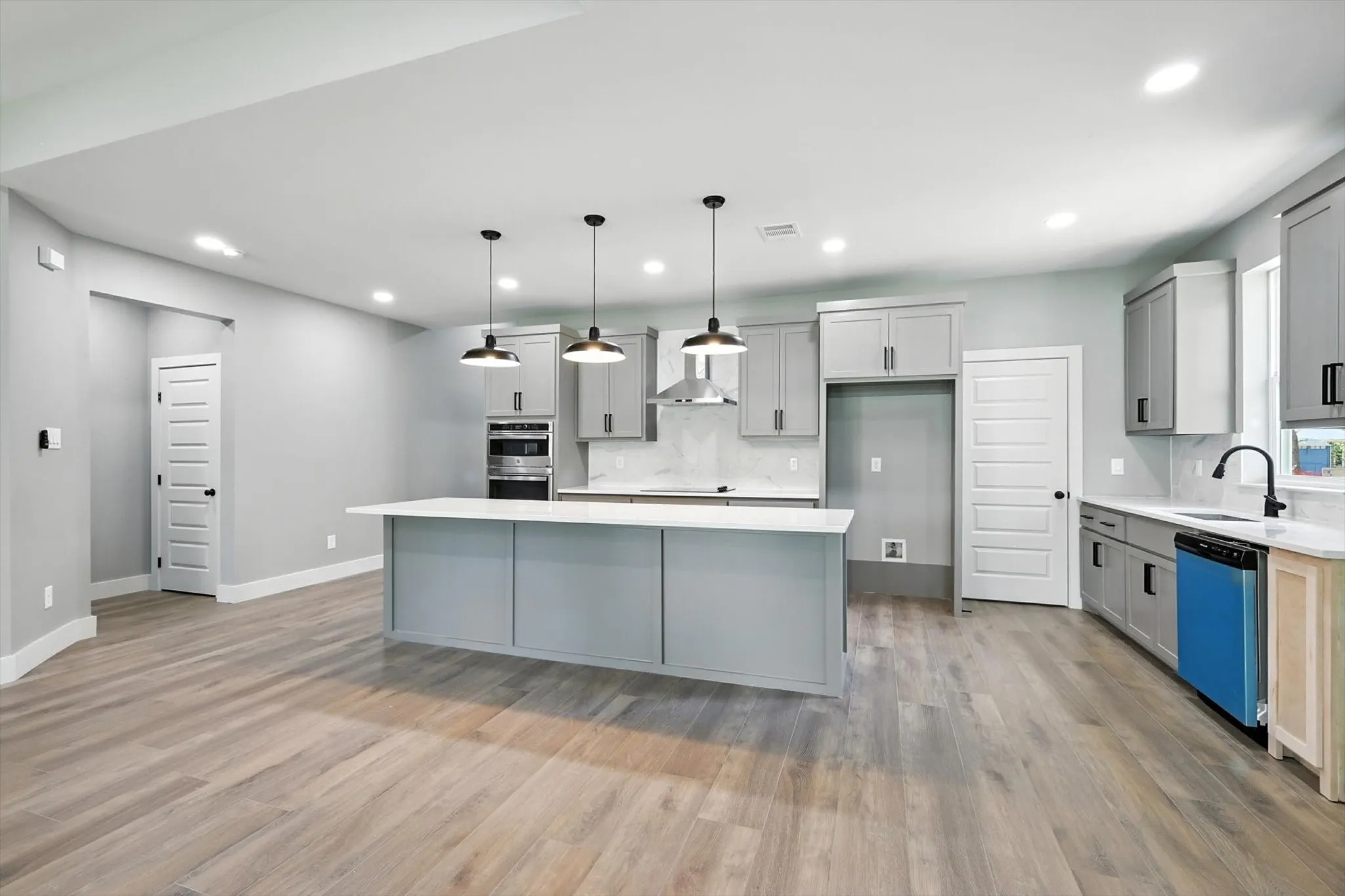 Kitchen featuring gray cabinetry, backsplash, hanging light fixtures, dishwashing machine, and recessed lighting
