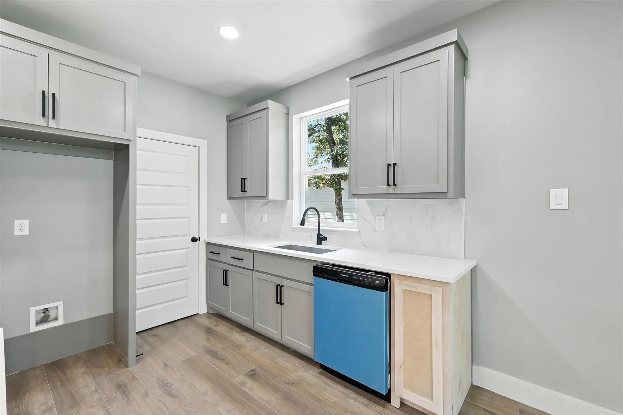 Kitchen with dishwasher, light wood-style floors, backsplash, recessed lighting, and light stone counters