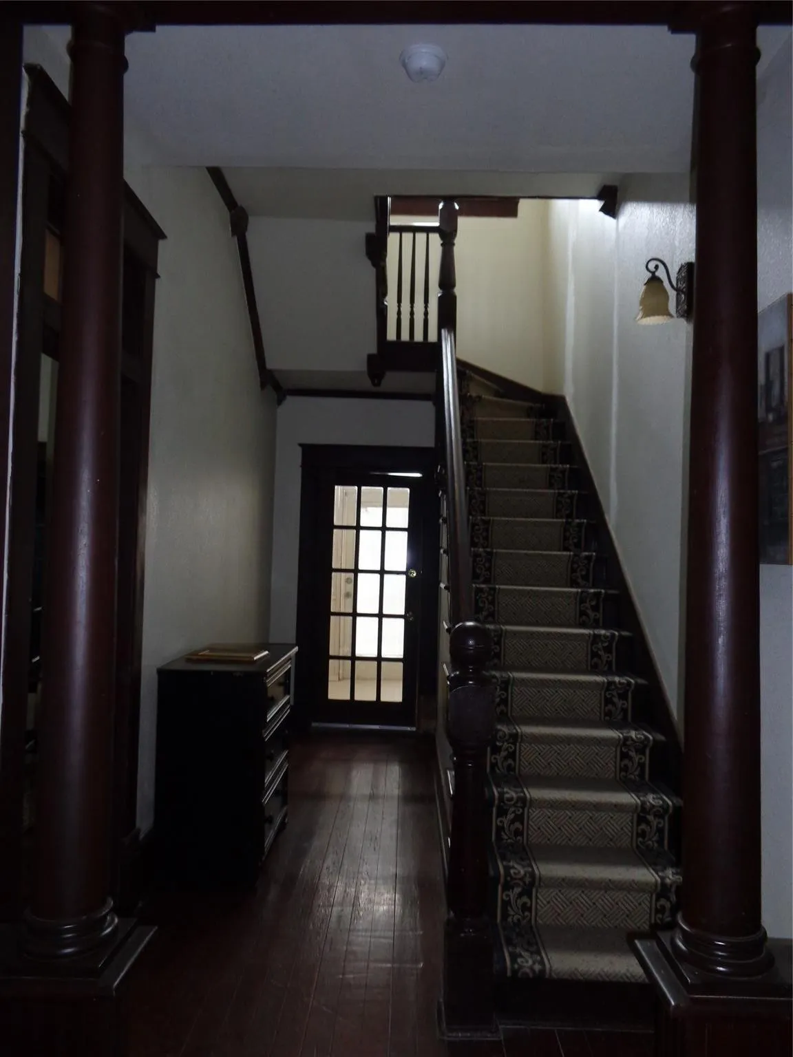 Staircase featuring wood-type flooring and ornate columns