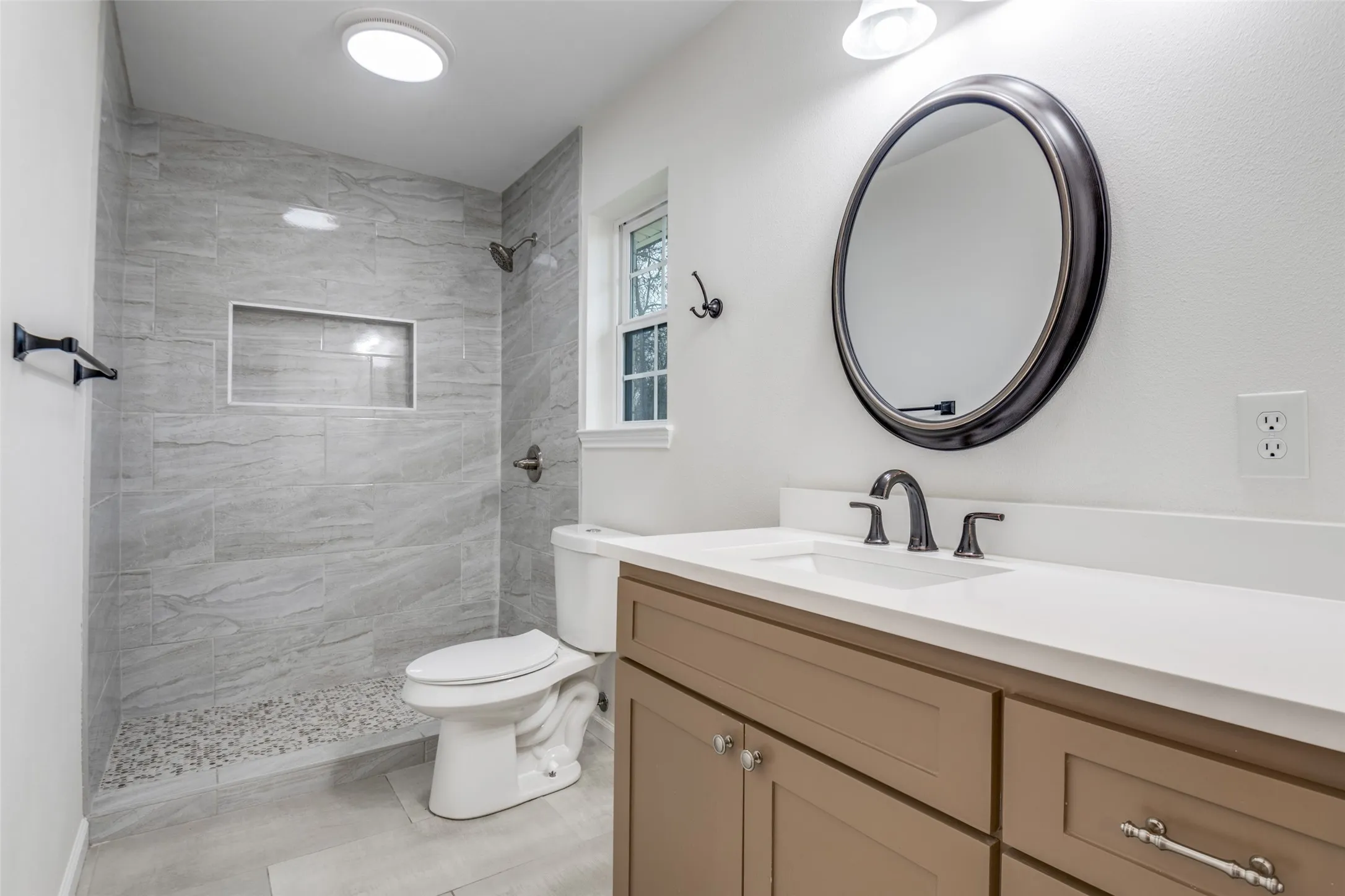 Bathroom featuring vanity, a tile shower, and vaulted ceiling