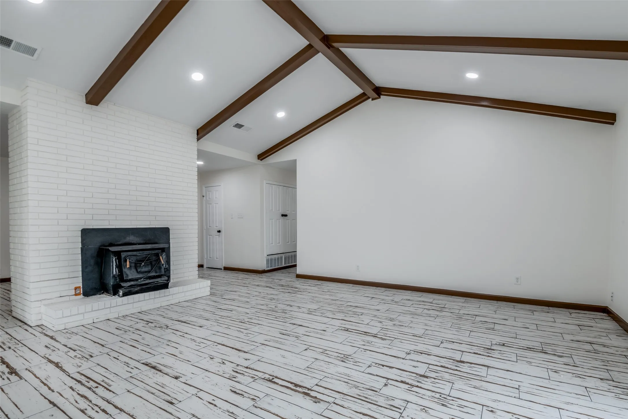 Unfurnished living room featuring recessed lighting, wood tiled floors, and a brick fireplace