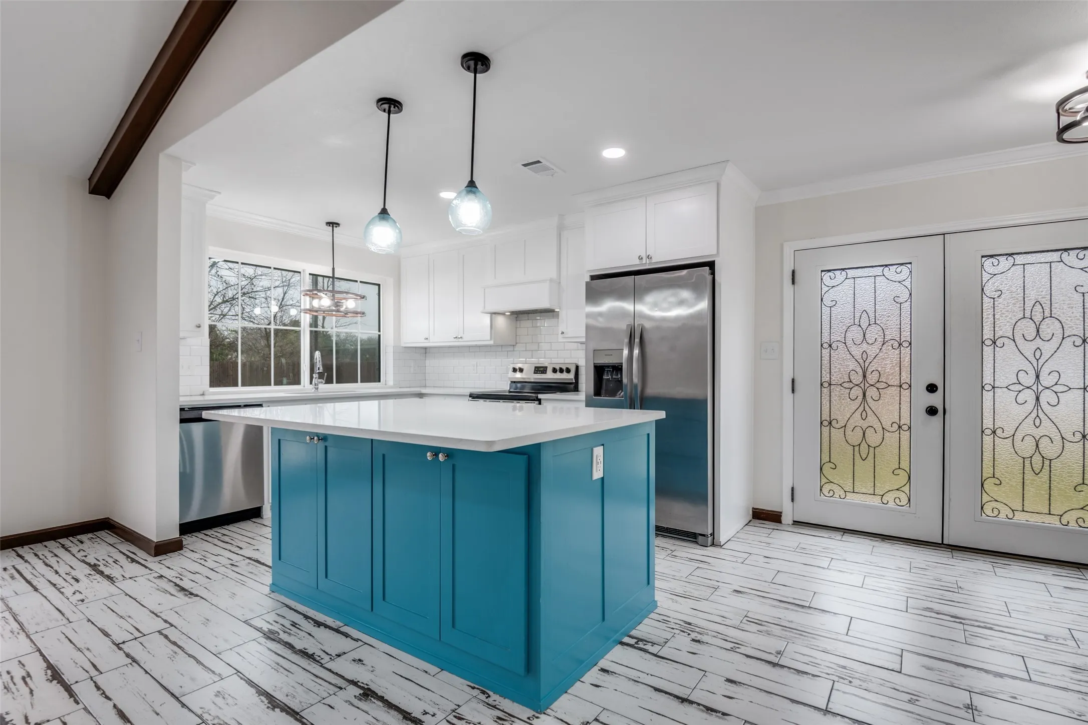 Kitchen featuring blue cabinets, a kitchen island, stainless steel appliances, crown molding, and white cabinetry