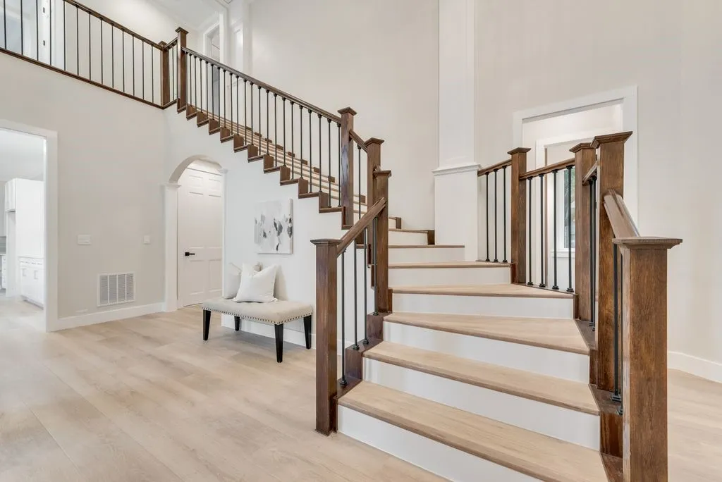 Grand entryway featuring a staircase with wood treads, white risers, and a wrought iron and wood railing