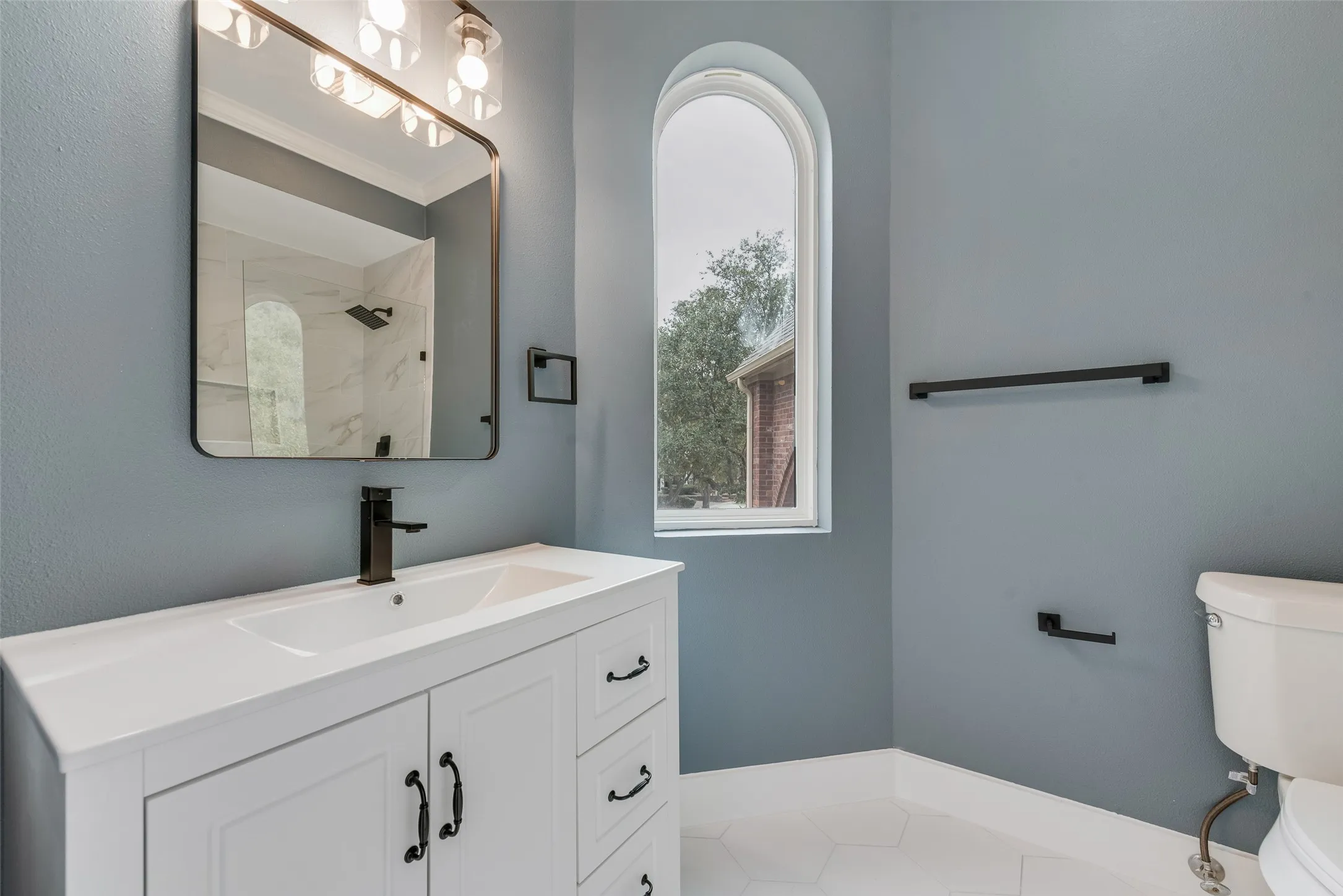 Full bath with vanity, light tile patterned floors, crown molding, and a shower