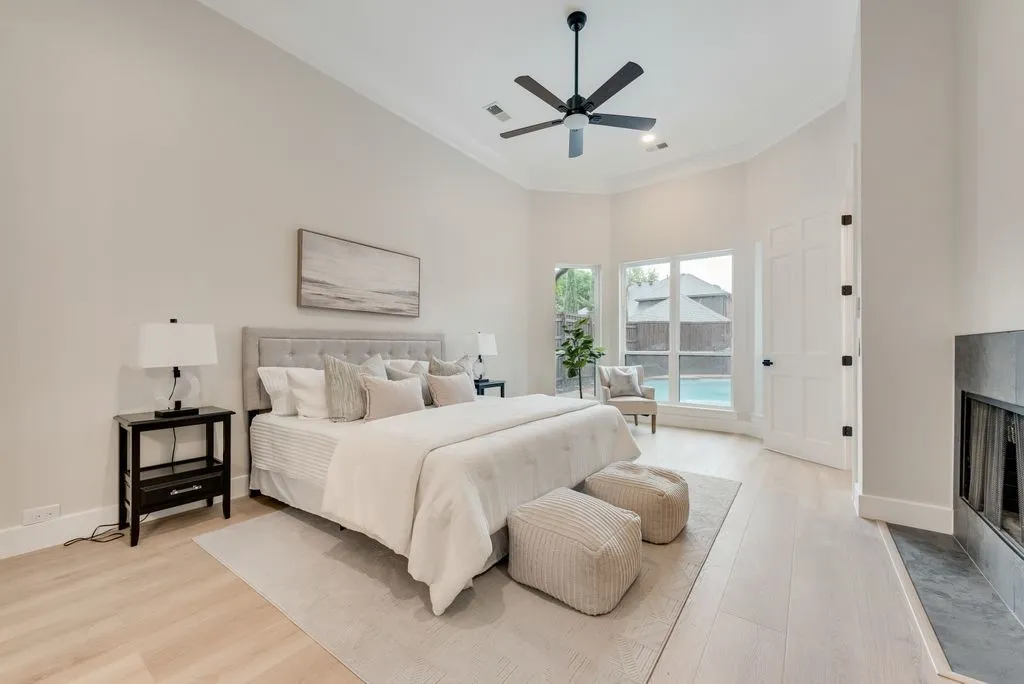This inviting room features light-toned flooring and a high ceiling with a ceiling fan