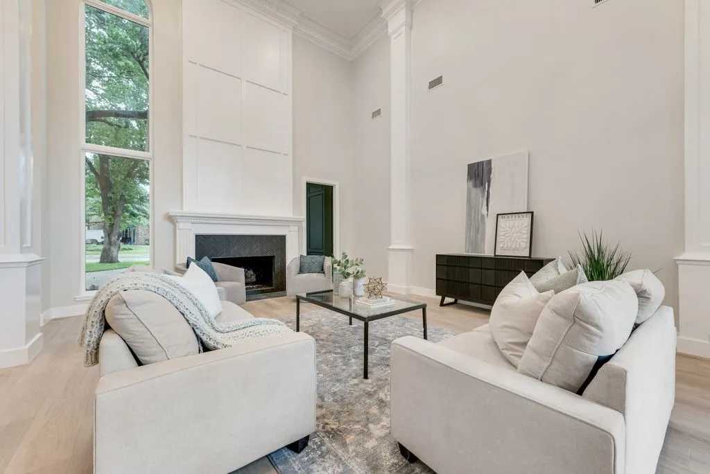 Spacious living area featuring high ceilings, a fireplace with a dark stone surround, and an expansive window