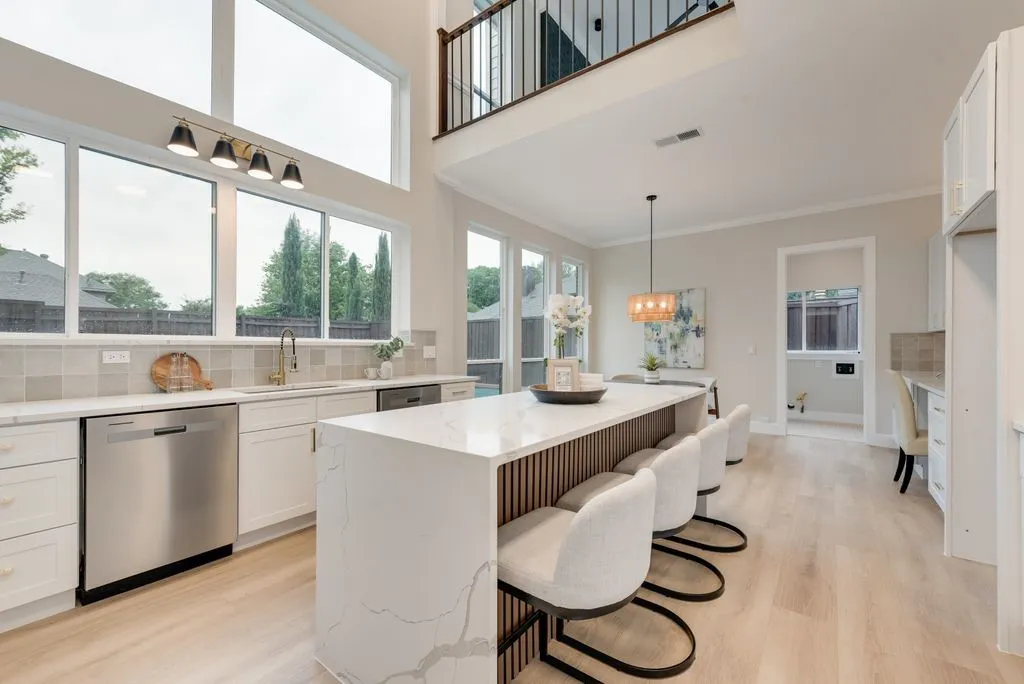 The kitchen features white cabinetry, stainless steel appliances, and a large island with a quartz countertop and seating