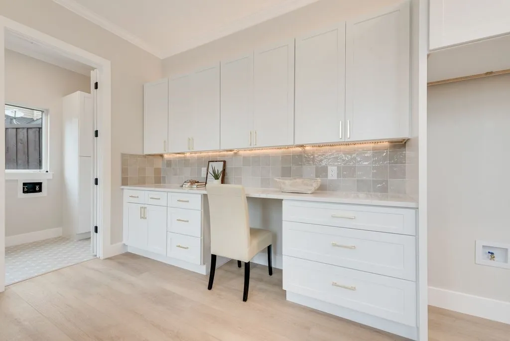 This room features extensive white cabinetry, a light-colored countertop, and a tiled backsplash