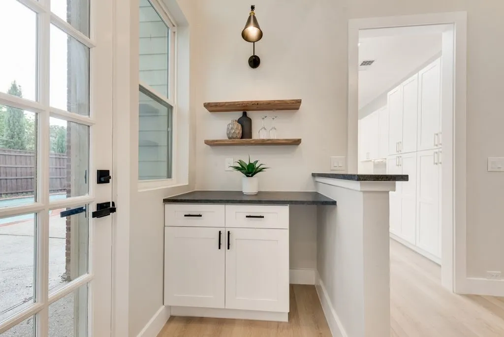 Entryway featuring a white French door, a window providing natural light, a built-in cabinet with a dark countertop, and decorative wooden shelving