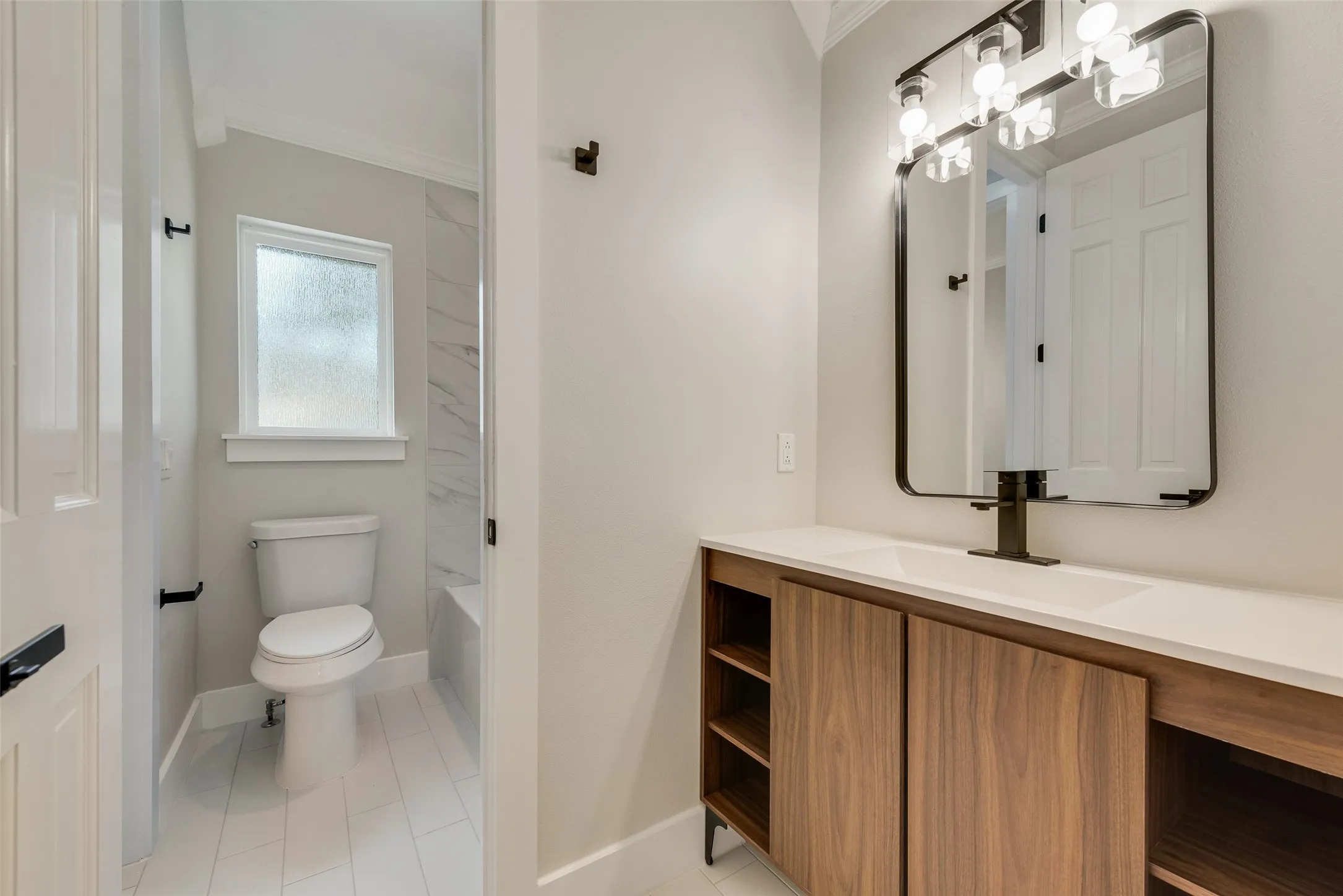 Bathroom with vanity, ornamental molding, bathtub / shower combination, and light tile patterned flooring