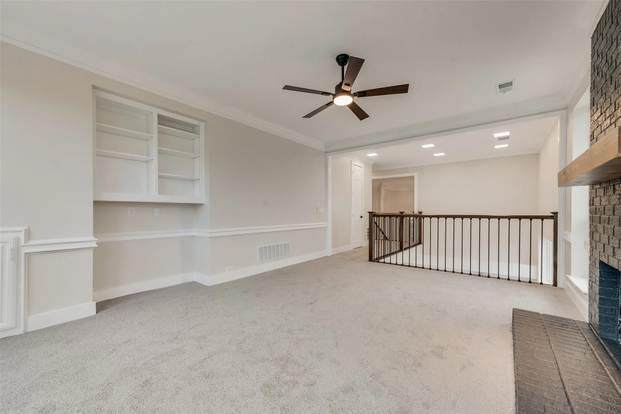 Empty room with crown molding, a ceiling fan, a fireplace, and light colored carpet