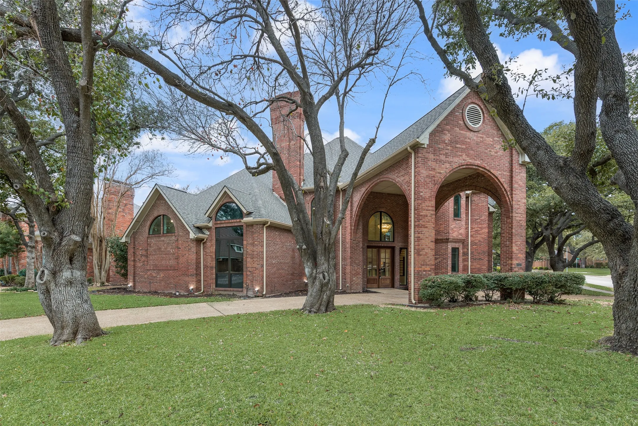 View of front facade featuring a front yard, brick siding, a chimney, and french doors