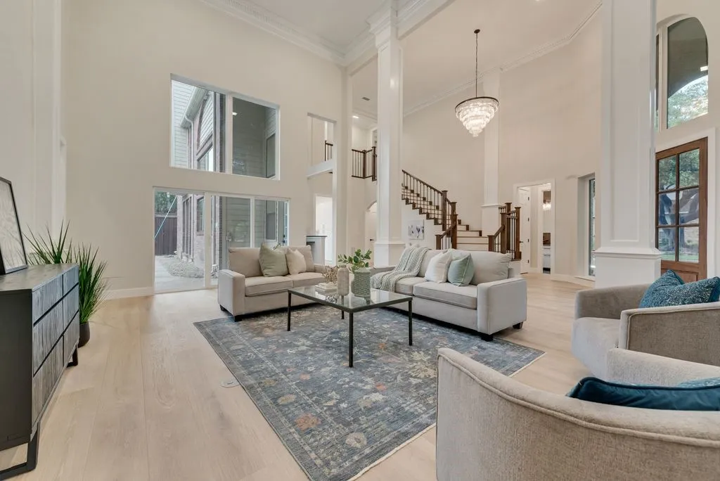 The property features an expansive living area with high ceilings, light wood flooring, and a large chandelier
