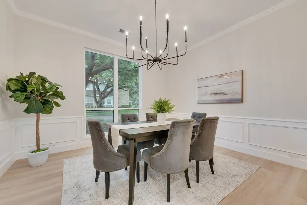 The dining area features light-colored walls, crown molding, and wainscoting
