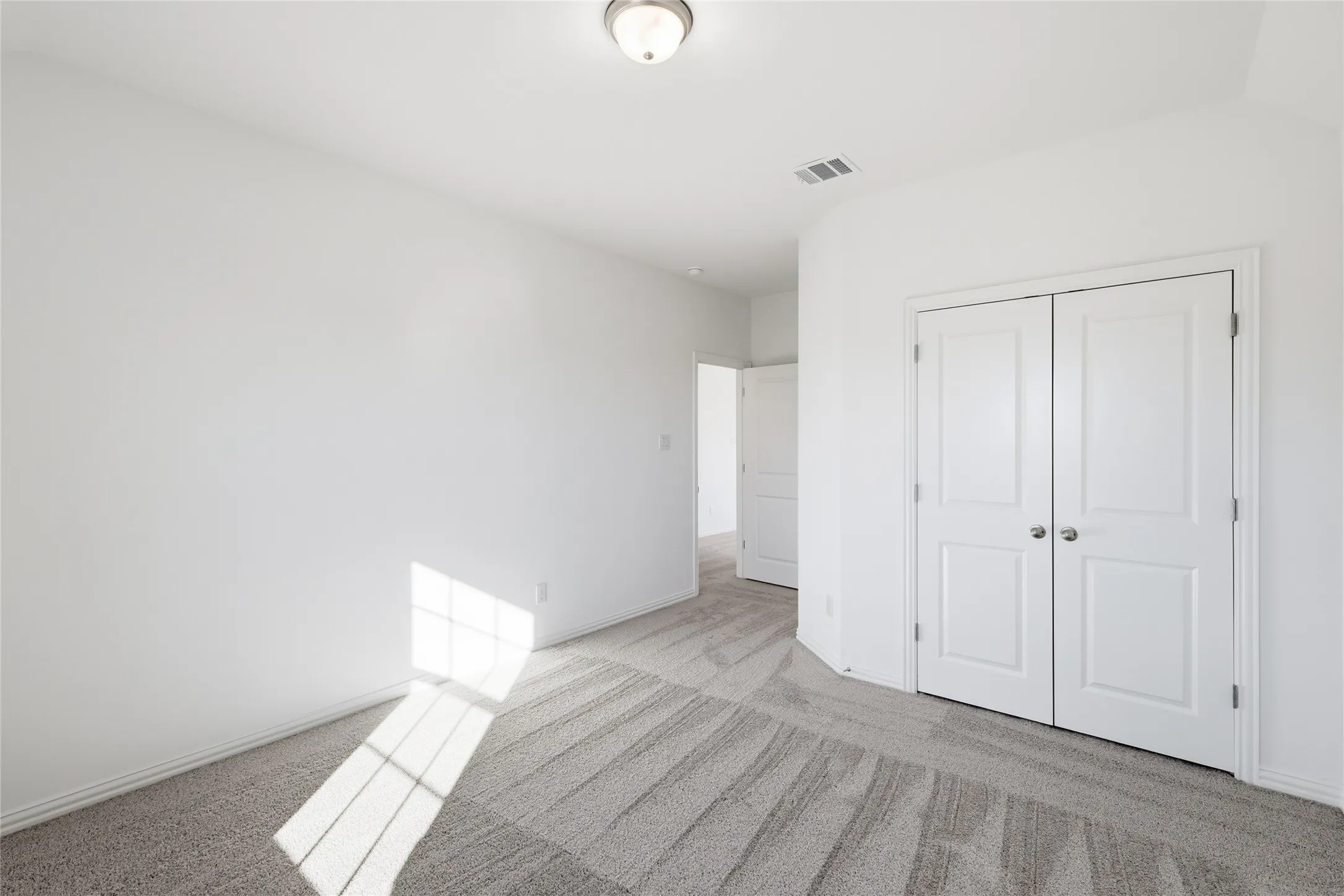 Neutral-toned room featuring a semi-flush ceiling light, white walls, and gray patterned carpet
