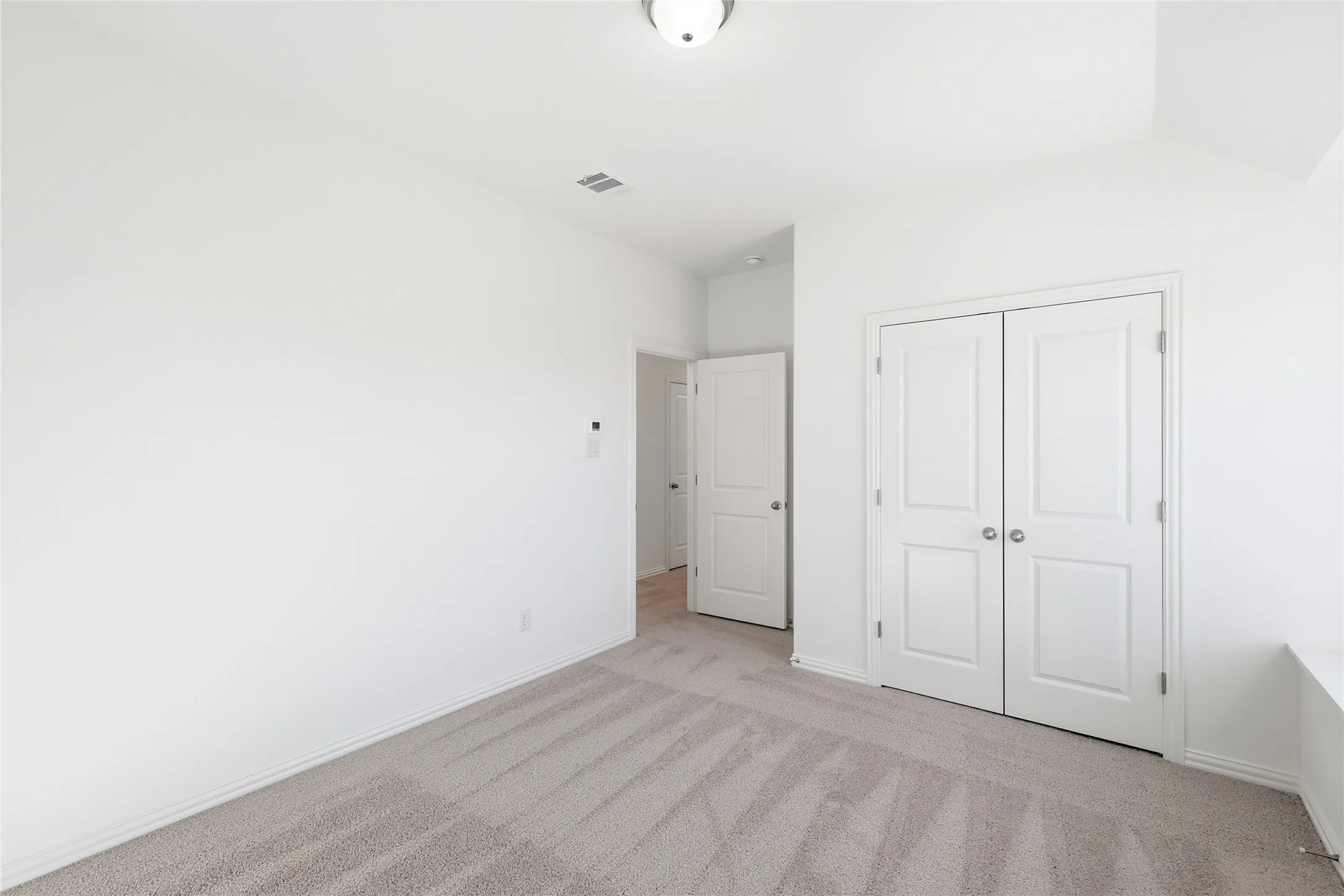Neutral-toned carpeted interior space featuring white walls and trim