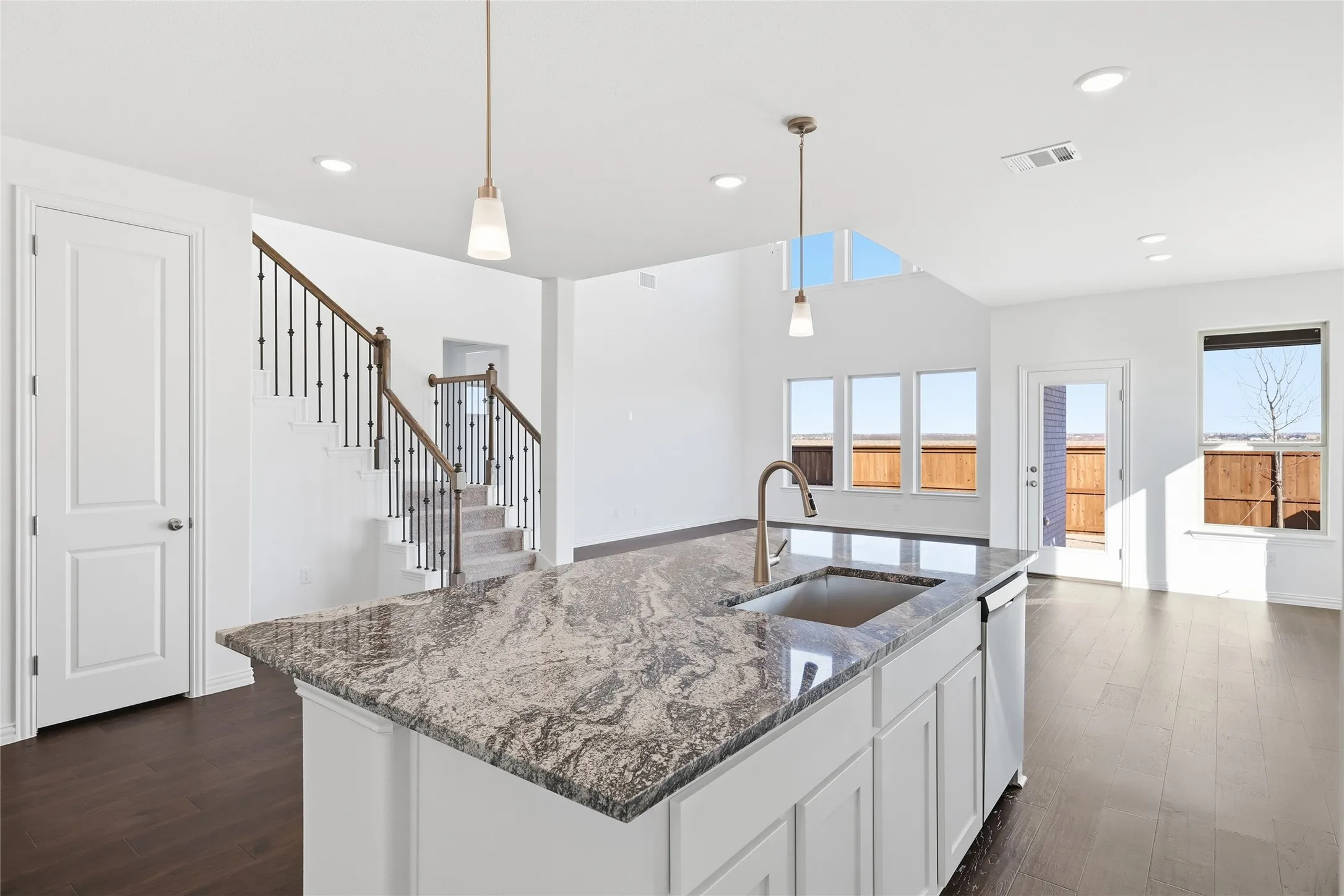 Kitchen island featuring a single-basin sink, brushed nickel faucet, and a patterned stone countertop